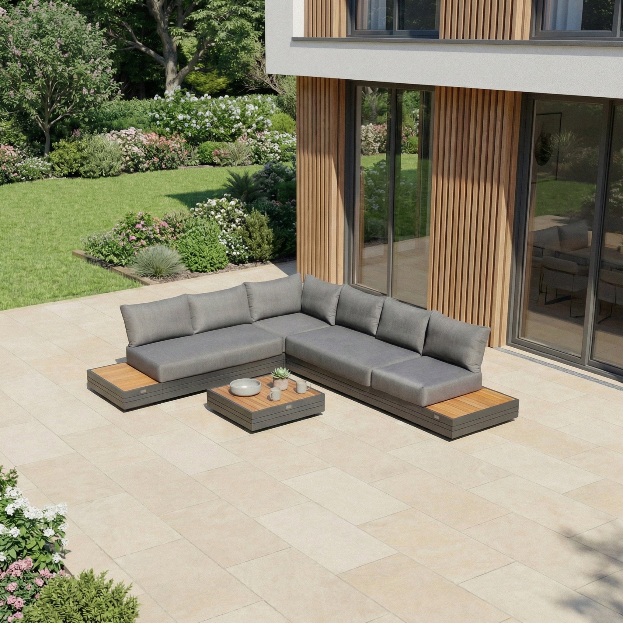 Modern outdoor patio featuring the Panama Luxury Outdoor L-Shape Corner Group Set in Charcoal, a low coffee table, and a garden backdrop.