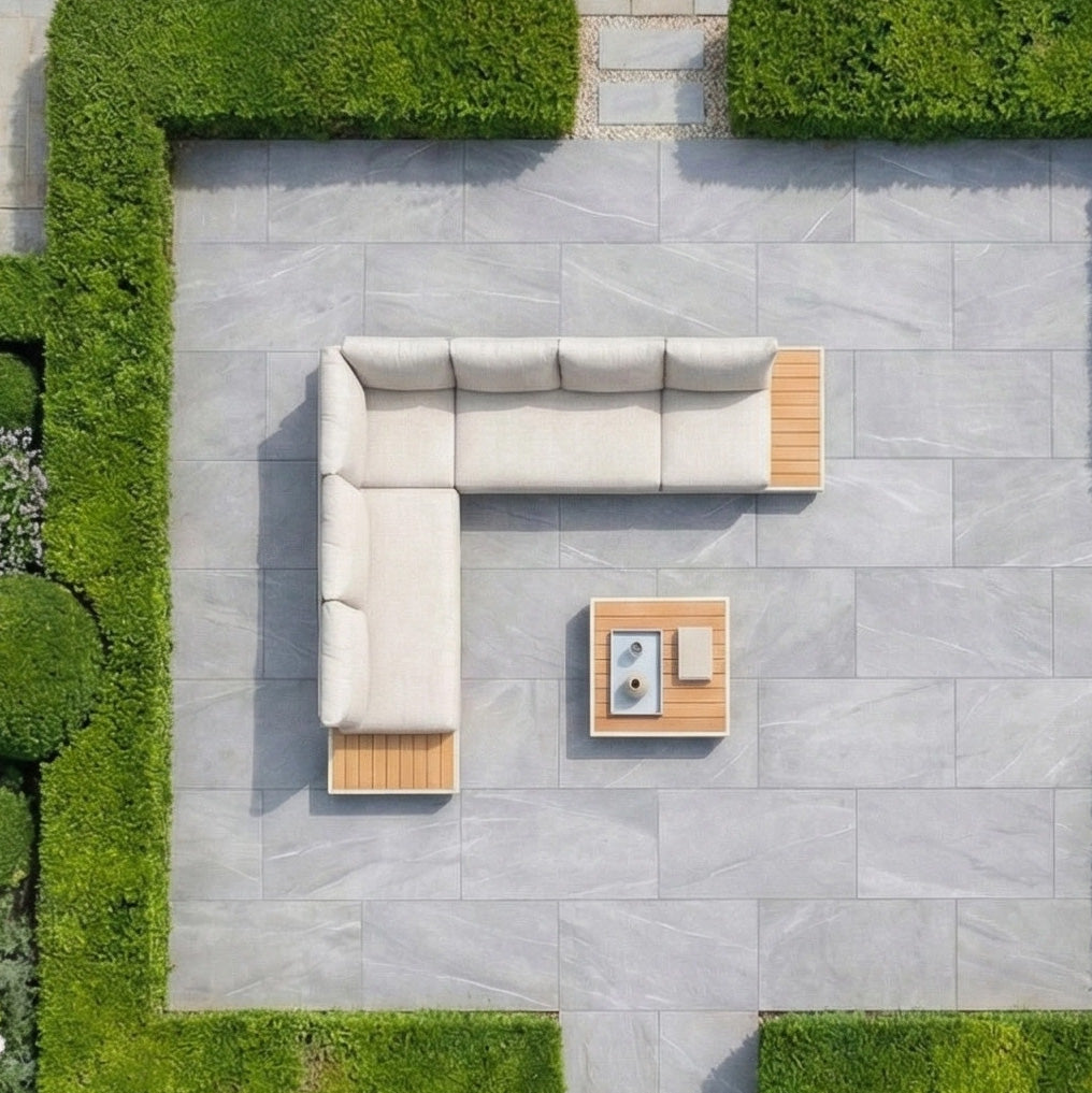 Aerial view of a Panama Luxury Outdoor L-Shape Corner Group Set in Latte with table on a gray patio, surrounded by neatly trimmed green hedges.