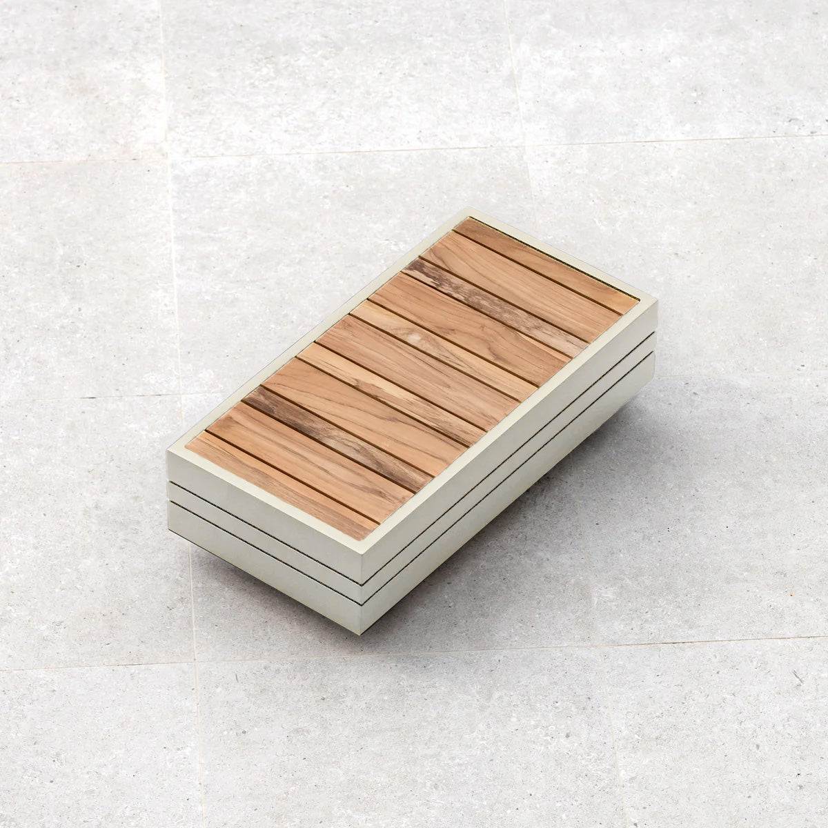 A rectangular object with a wooden top and white sides, reminiscent of the Panama Luxury Outdoor L-Shape Corner Group Set in Latte from Harbour Lifestyle, resting on a light gray tiled surface.