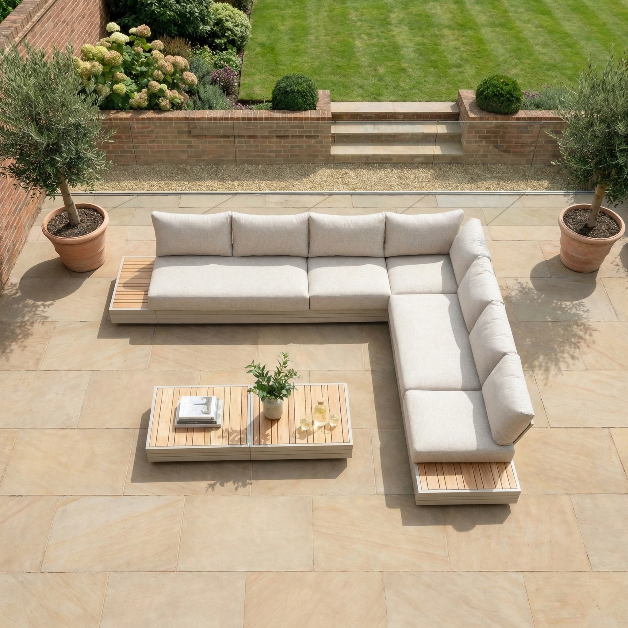 Modern outdoor patio with a Panama Luxury Outdoor Large Corner Group Set in Latte, coffee table, potted trees, and a neatly trimmed lawn in the background.