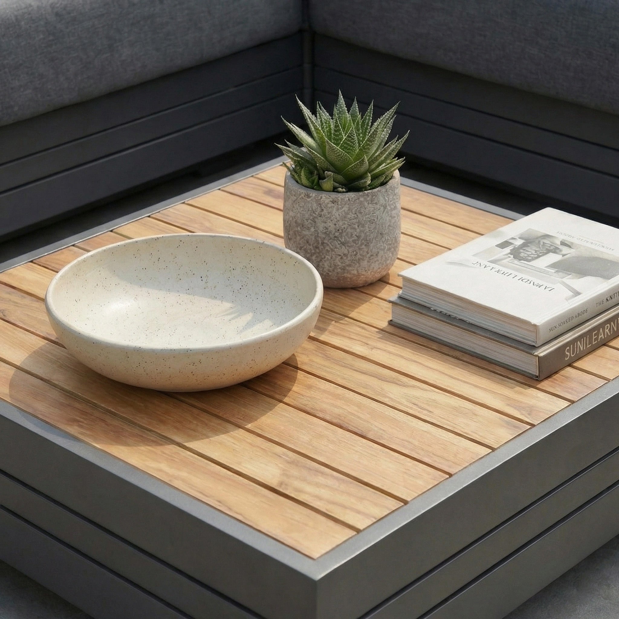 The Panama Teak Coffee Table styled with a succulent, ceramic bowl, and stacked books creates a modern vibe, making it an ideal choice for a luxury outdoor coffee table or a chic teak garden table.