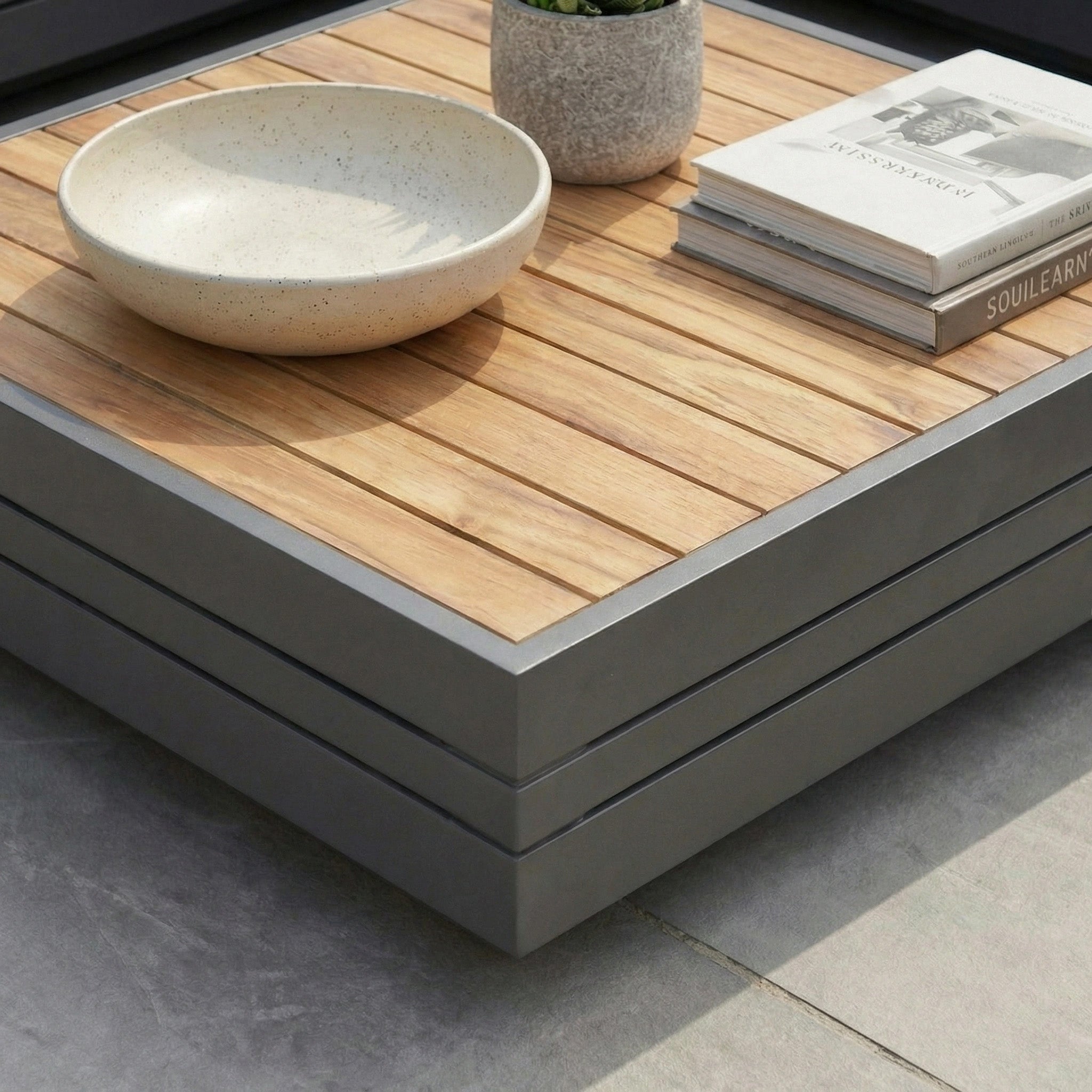 Panama Teak Coffee Table topped with a ceramic bowl, potted plant, and two stacked books—an elegant addition to your space.