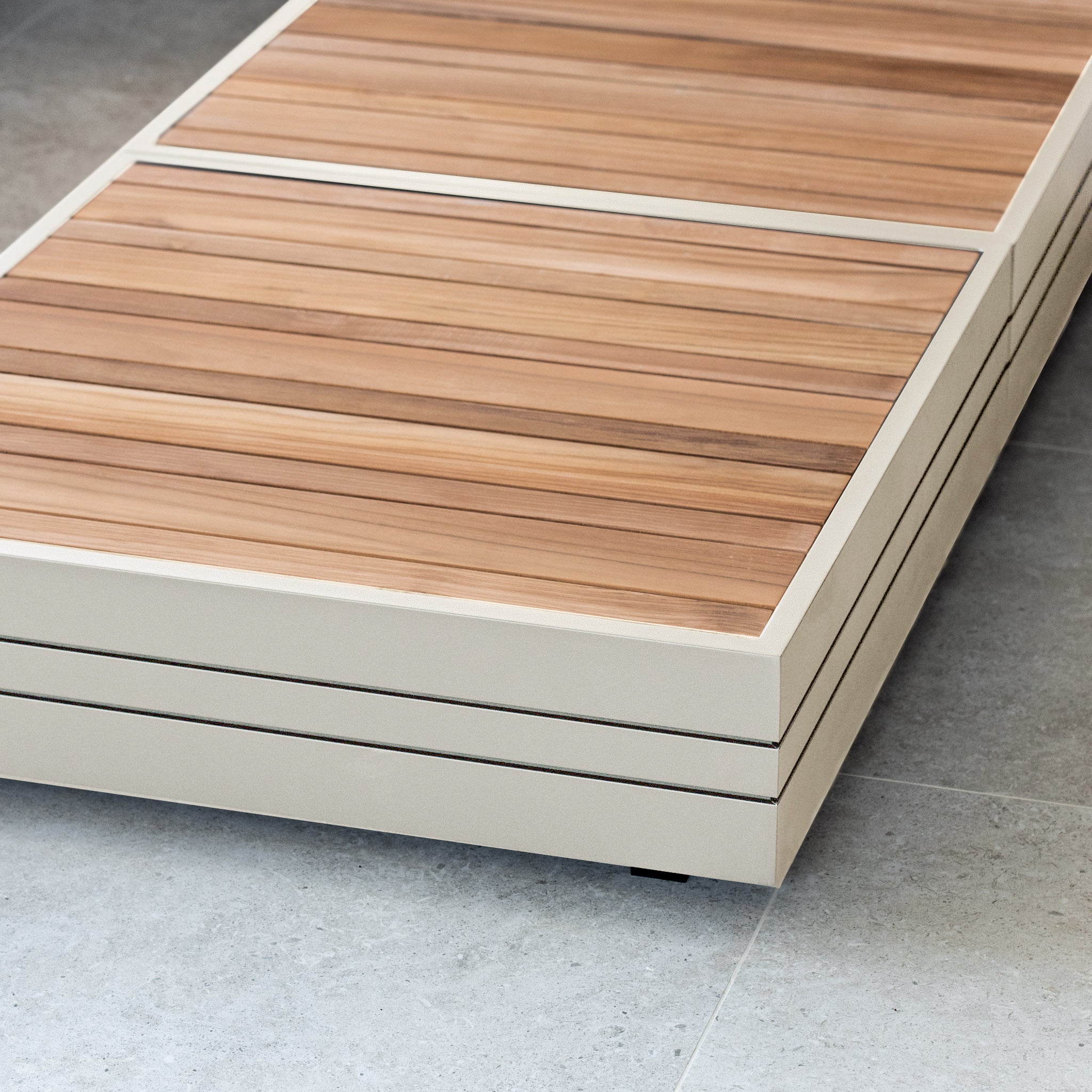 Close-up of a modern wooden bench on a light gray tiled floor. The bench, reminiscent of the exquisite craftsmanship of the Panama Teak Coffee Table in Latte, features light and dark wooden slats.