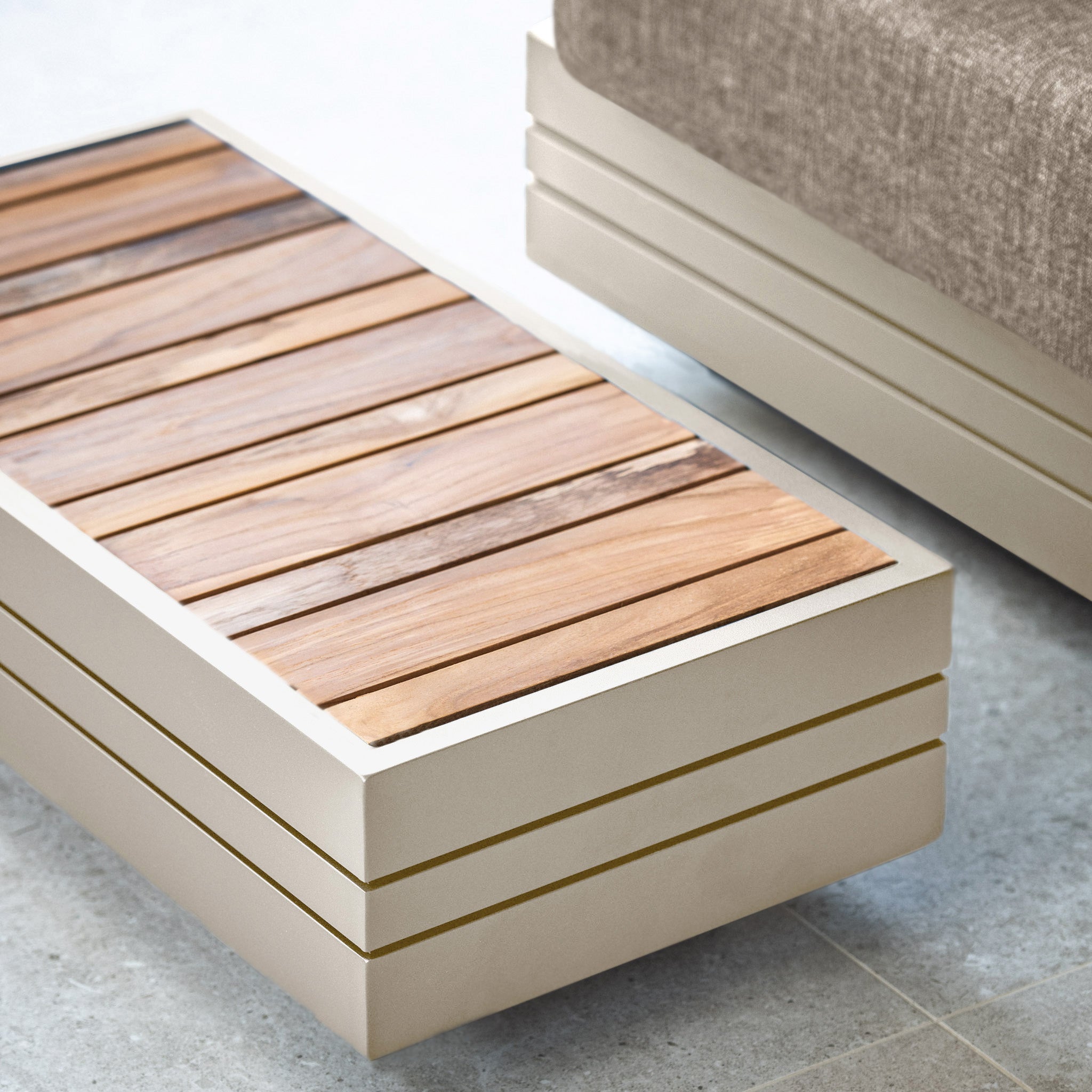 A modern coffee table with a wooden slat top and a beige frame, standing next to the curated elegance of the Panama Luxury Outdoor L-Shape Corner Group Set in Latte on a stone floor, embodies the sophistication of the Harbour Lifestyle Panama collection.