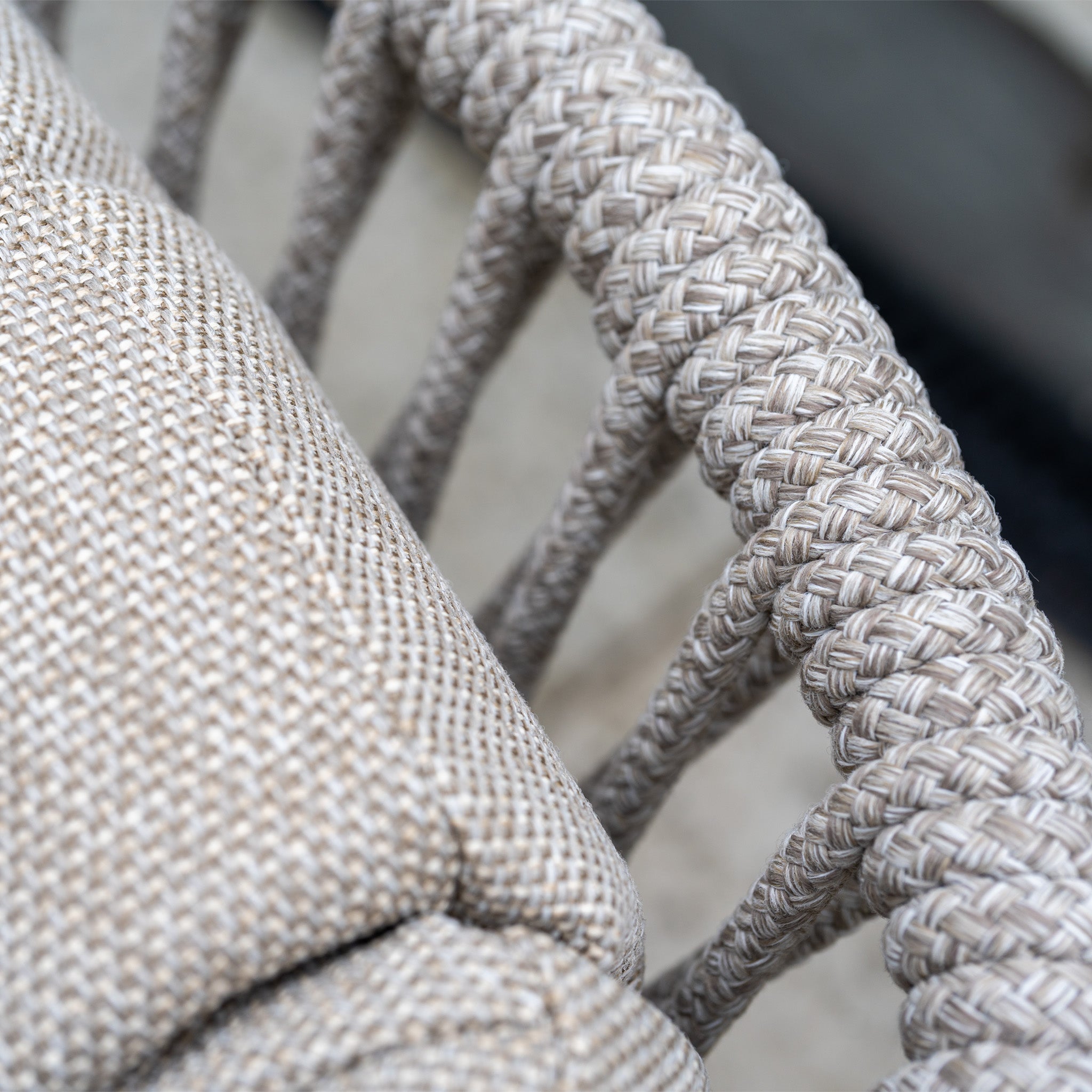 Close-up of a woven beige rope armrest and textured beige cushion on a chair, part of the Pello 4 Seat Round Dining Set with Albatross Table in Fawn—perfect for stylish outdoor dining.