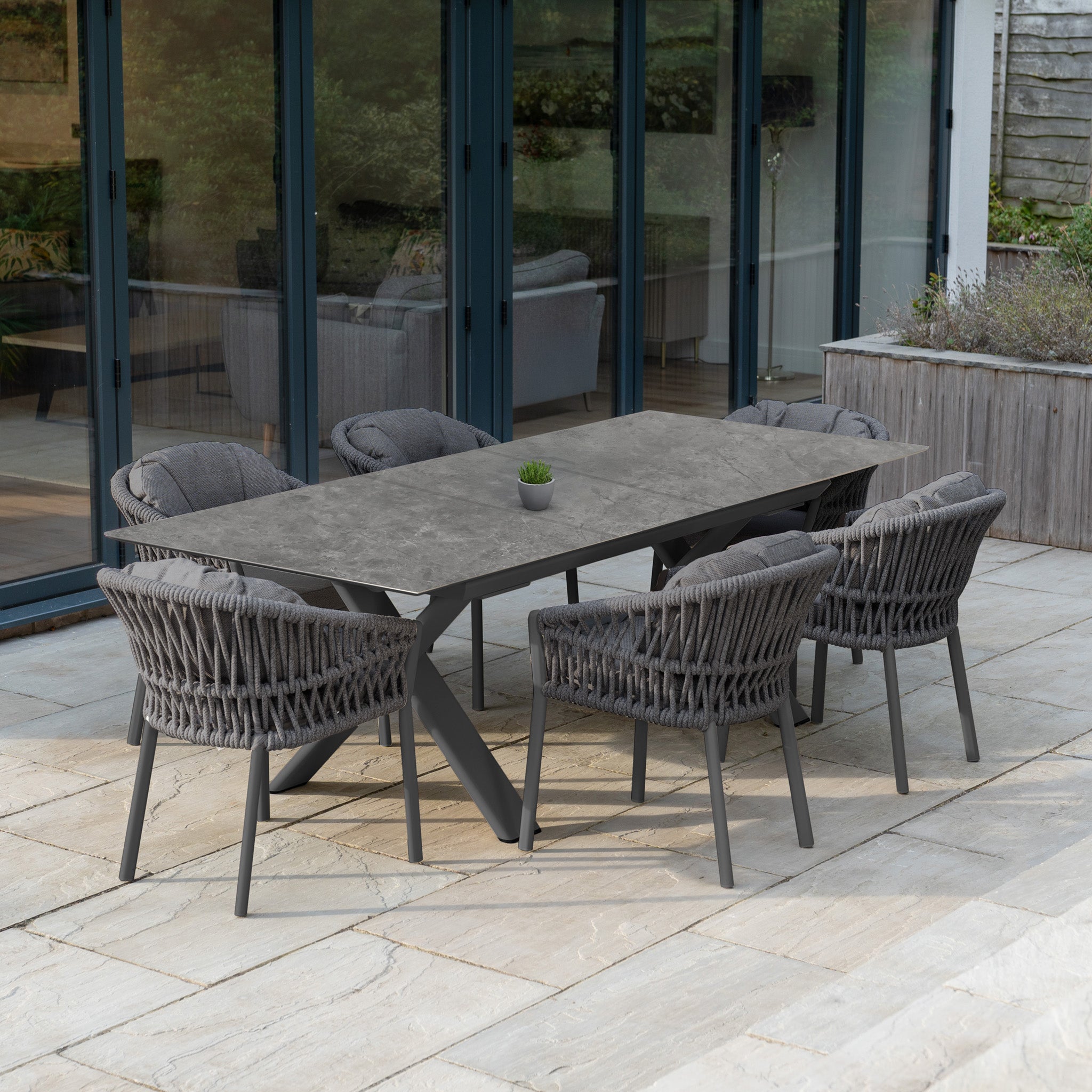 The Pello 6 Seat Dining Set with Albatross Extending Table in Grey offers cushioned chairs and a stylish table, perfect outdoor dining furniture for your stone patio.