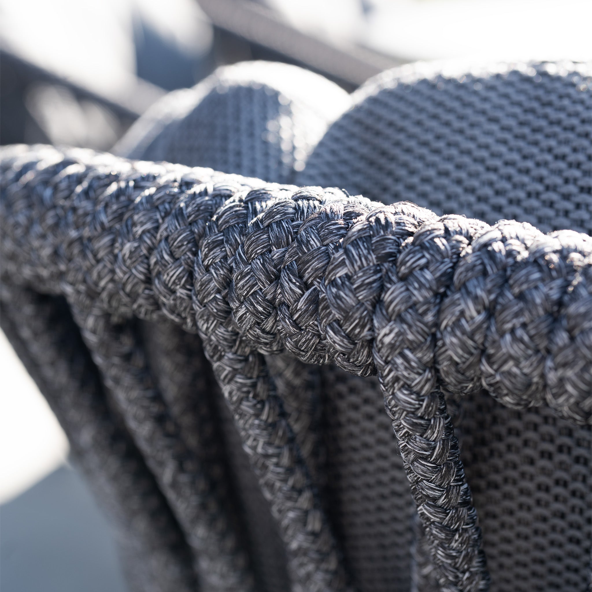 Close-up of a woven dark gray outdoor chair with textured rope and cushioned backrest, featured in our Pello 8 Seat Dining Set with Albatross Extending Table in Grey.