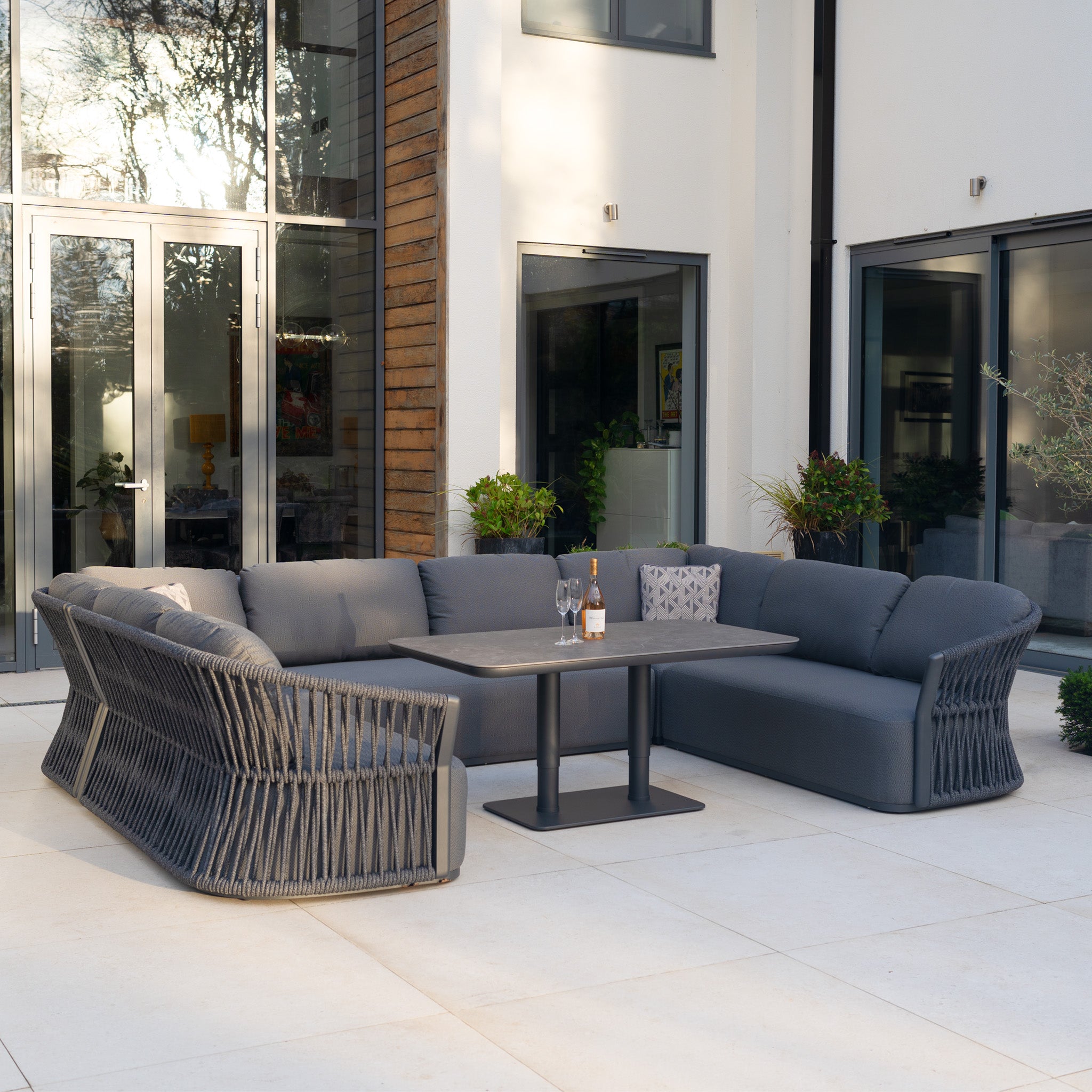 Modern outdoor patio featuring the Pello U-Shape Corner Sofa Set with Altura Rising Table in Grey—sleek, contemporary garden furniture perfect for relaxing and dining in style.