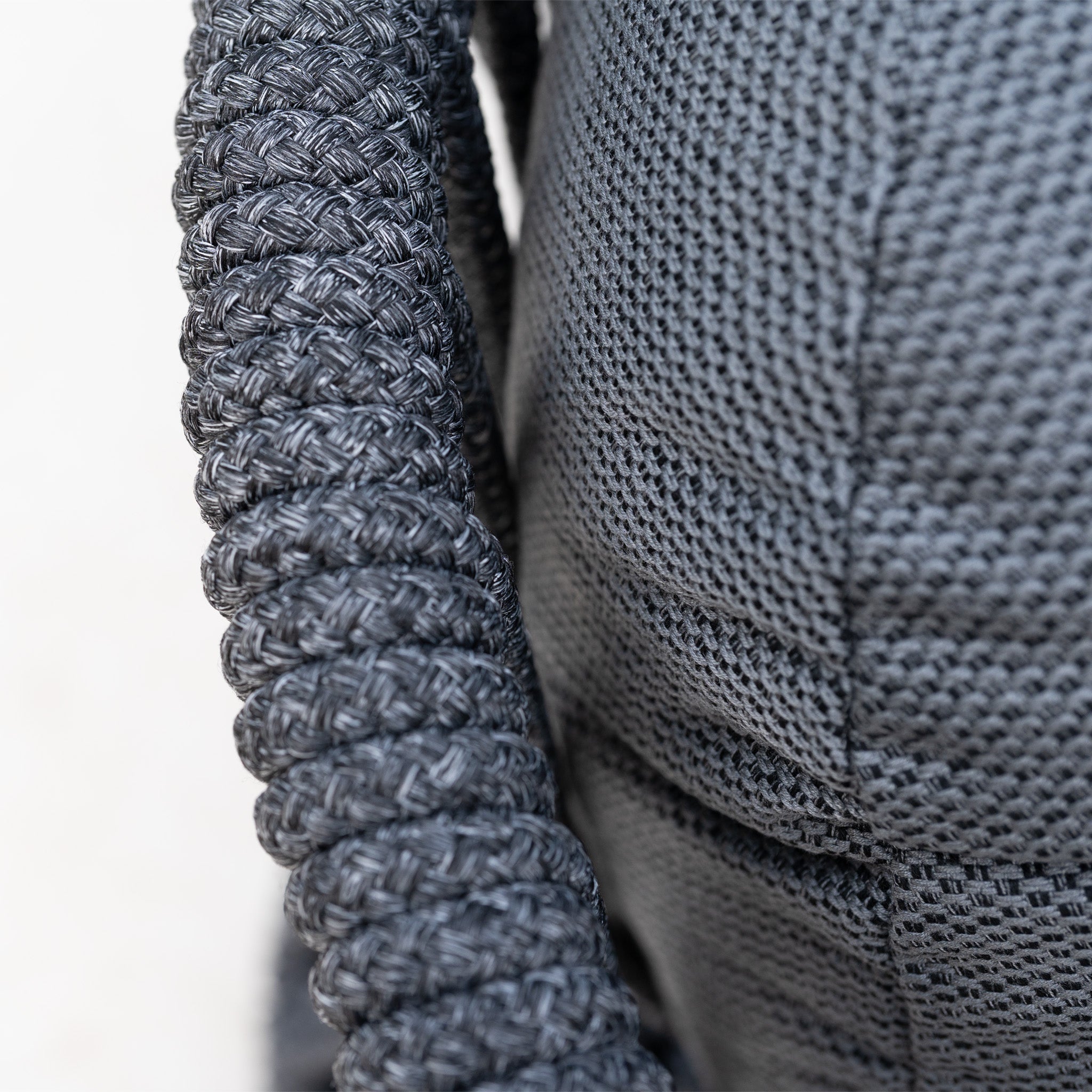 Close-up of a braided gray rope beside textured gray fabric, both with intricate patterns—perfect for elevating your garden space with the Pello U-Shape Corner Sofa Set with Altura Rising Table in Grey.