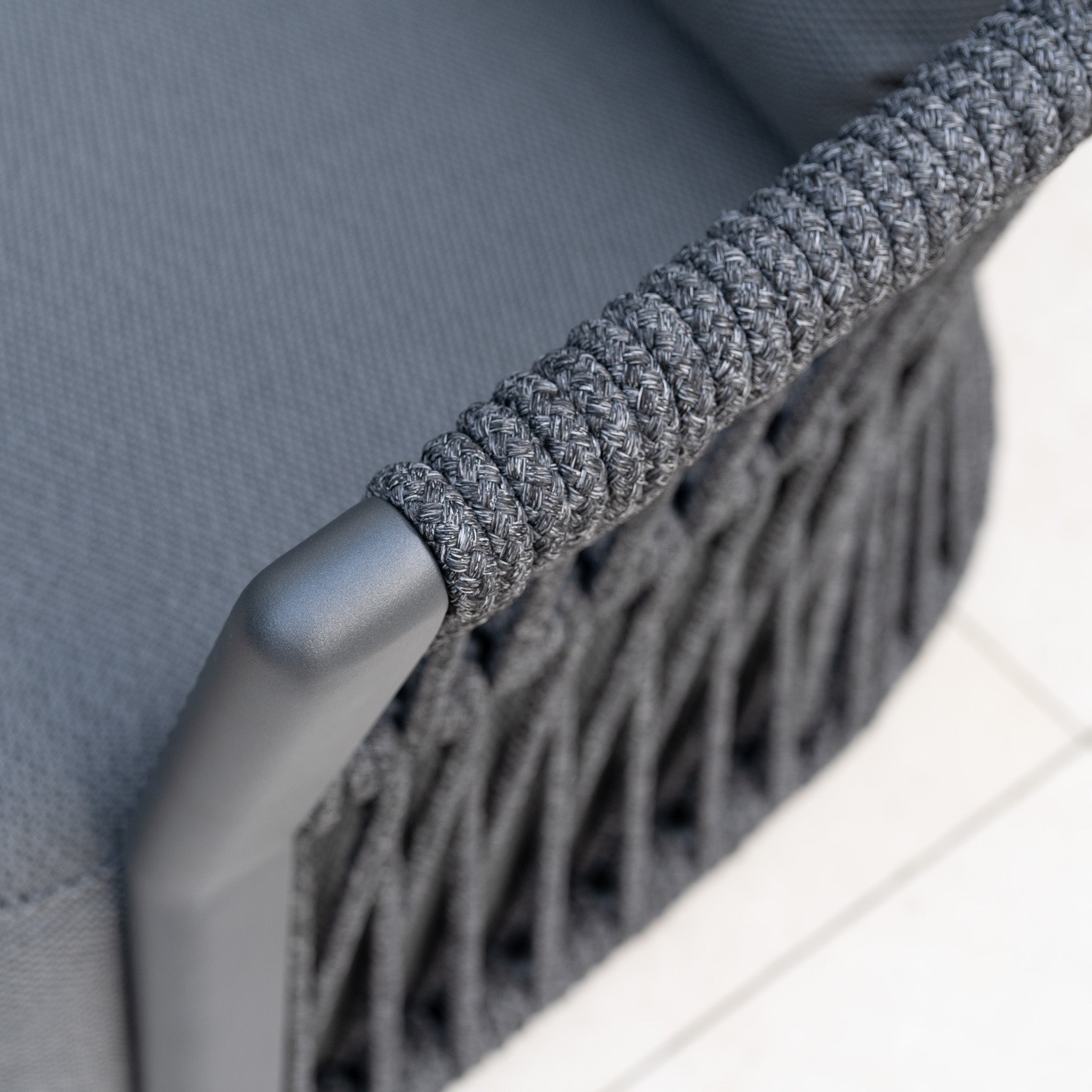 Close-up of the Pello U-Shape Corner Sofa Set with Altura Rising Table in Grey, featuring a dark gray woven rope armrest and textured fabric on a metal frame—ideal for enhancing your garden or outdoor dining space.