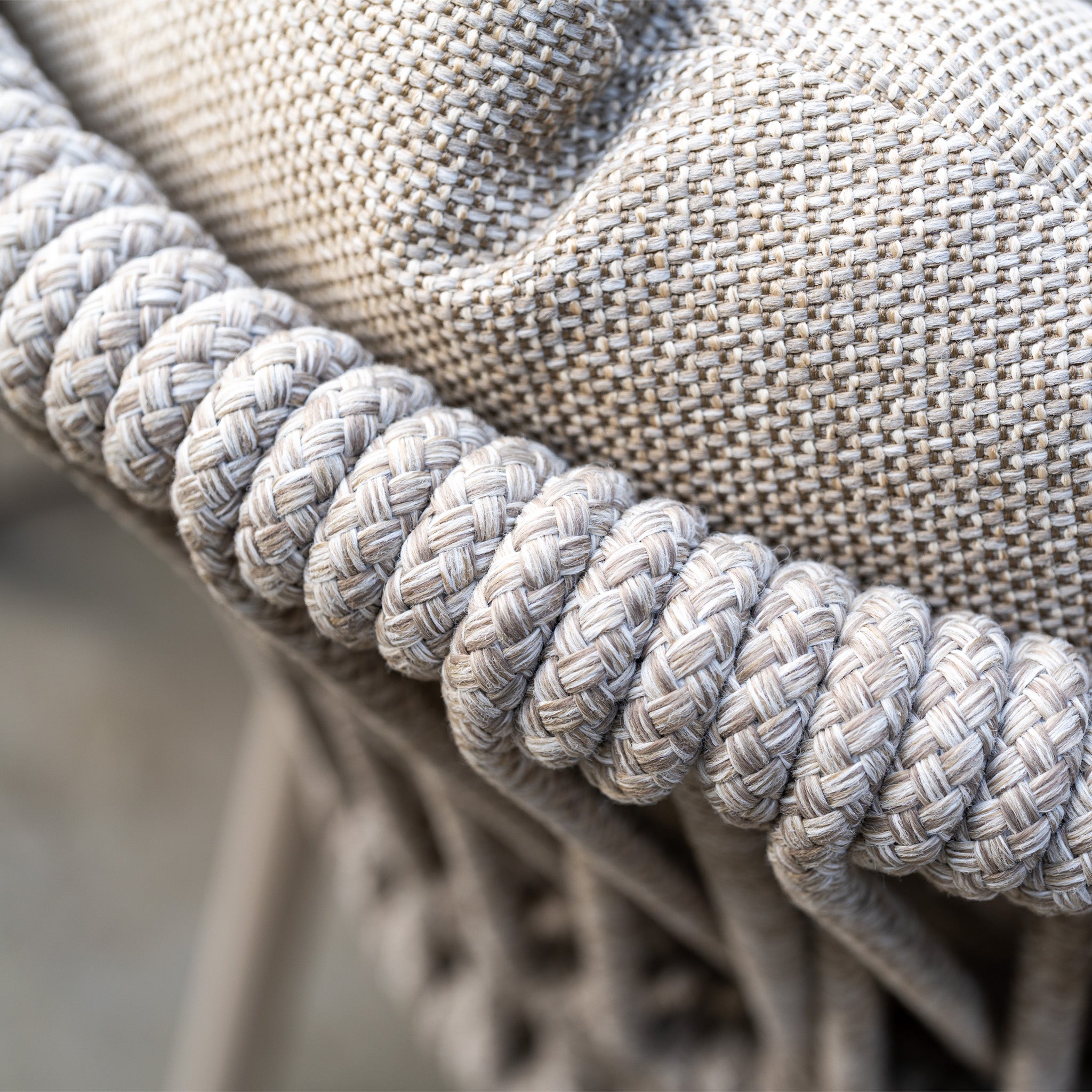 Close-up of a woven rope chair with a textured fabric cushion in neutral tones, featured in the weather-resistant Pello 6 Seat Oval Dining Set with Ceramic Table in Fawn.