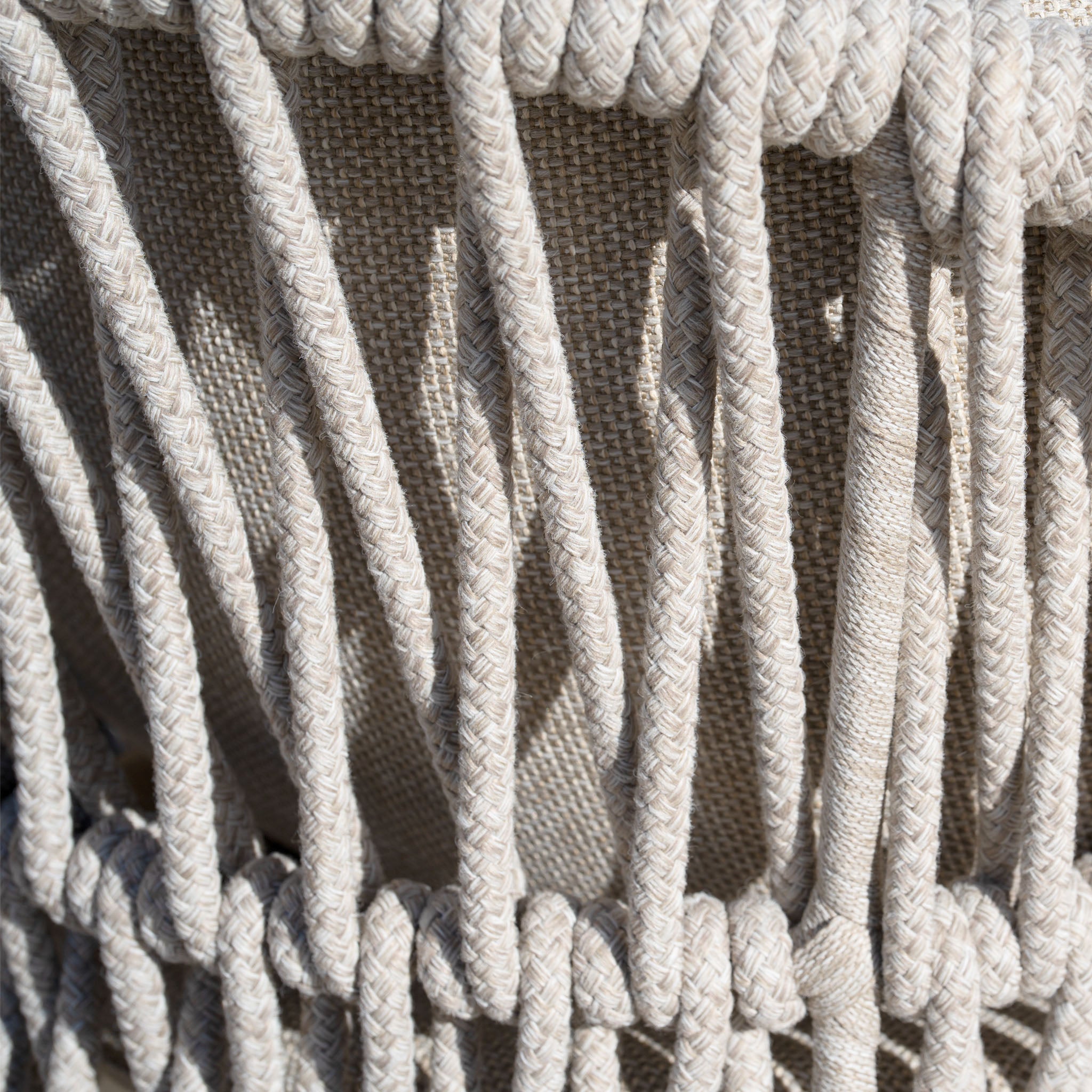 Close-up of beige woven rope pattern on textured fabric, featuring intricate loops and braids, similar to the detailing on the Pello 8 Seat Extending Dining Set with Ceramic Table in Fawn.