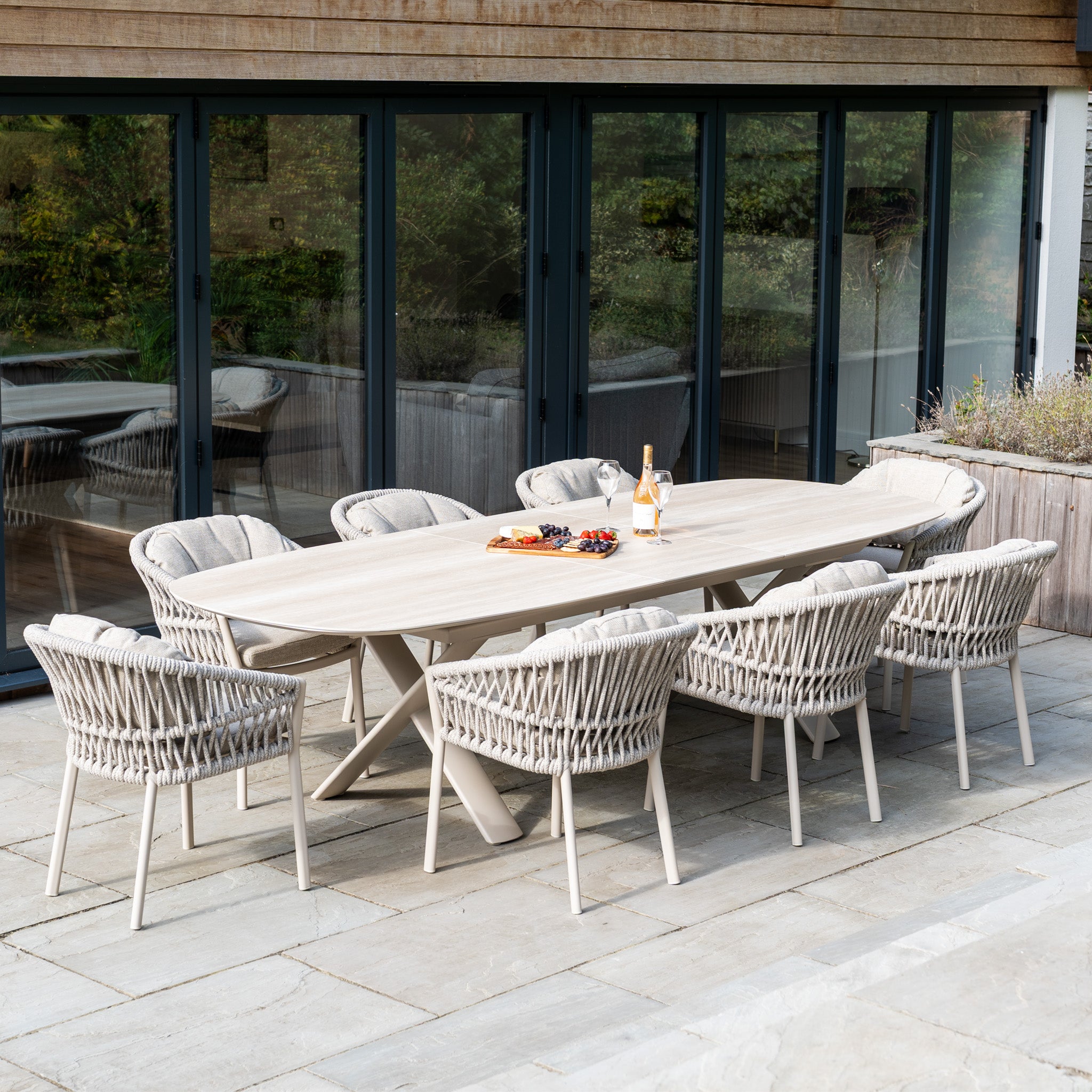 The Pello 8 Seat Oval Dining Set with Albatross Extending Table in Fawn features eight woven chairs—ideal durable garden furniture for entertaining on the patio by your glass doors.