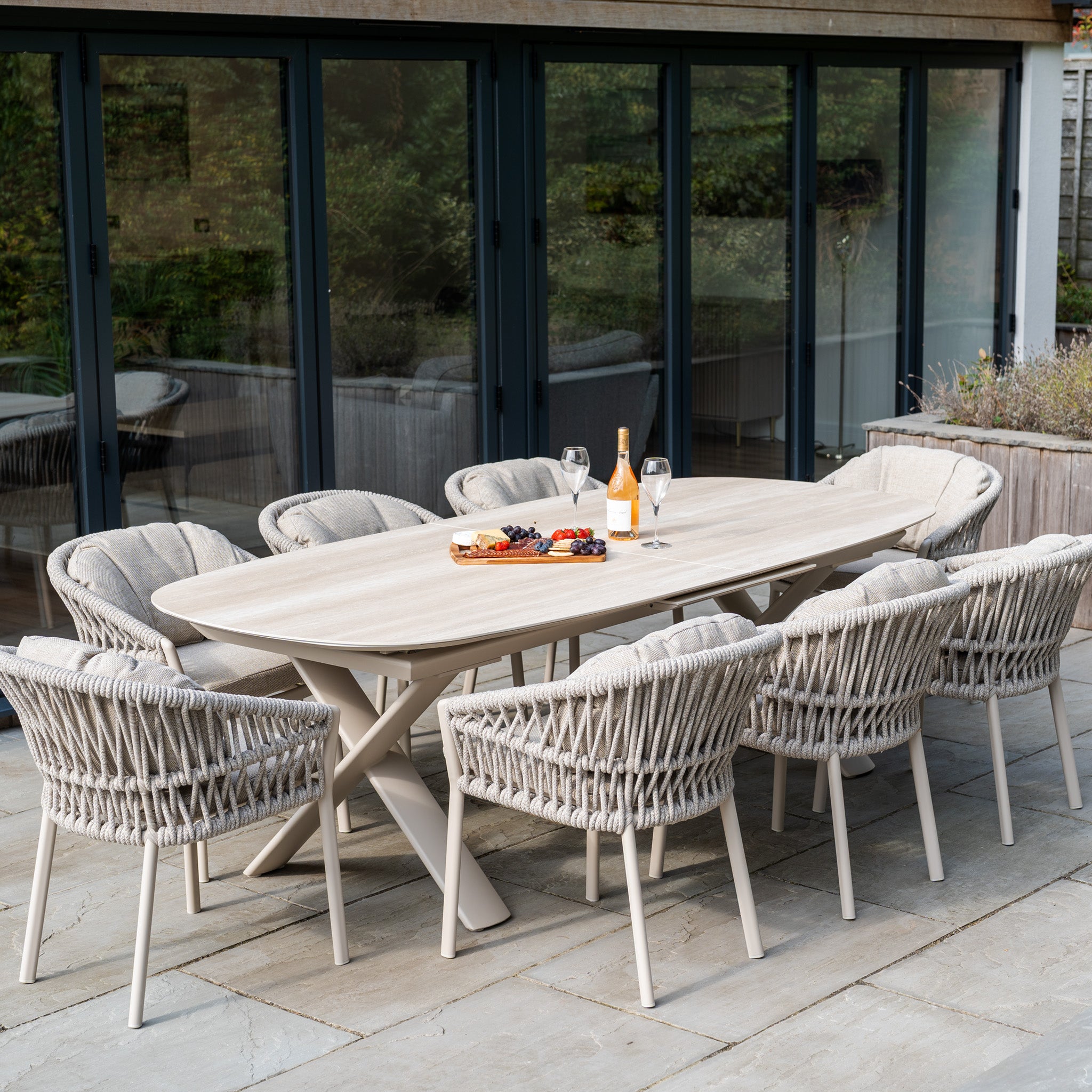 The Pello 8 Seat Oval Dining Set with Albatross Extending Table in Fawn offers style and comfort for your patio, featuring eight woven chairs—ideal for outdoor dining with wine, snacks, and friends near your sliding doors.