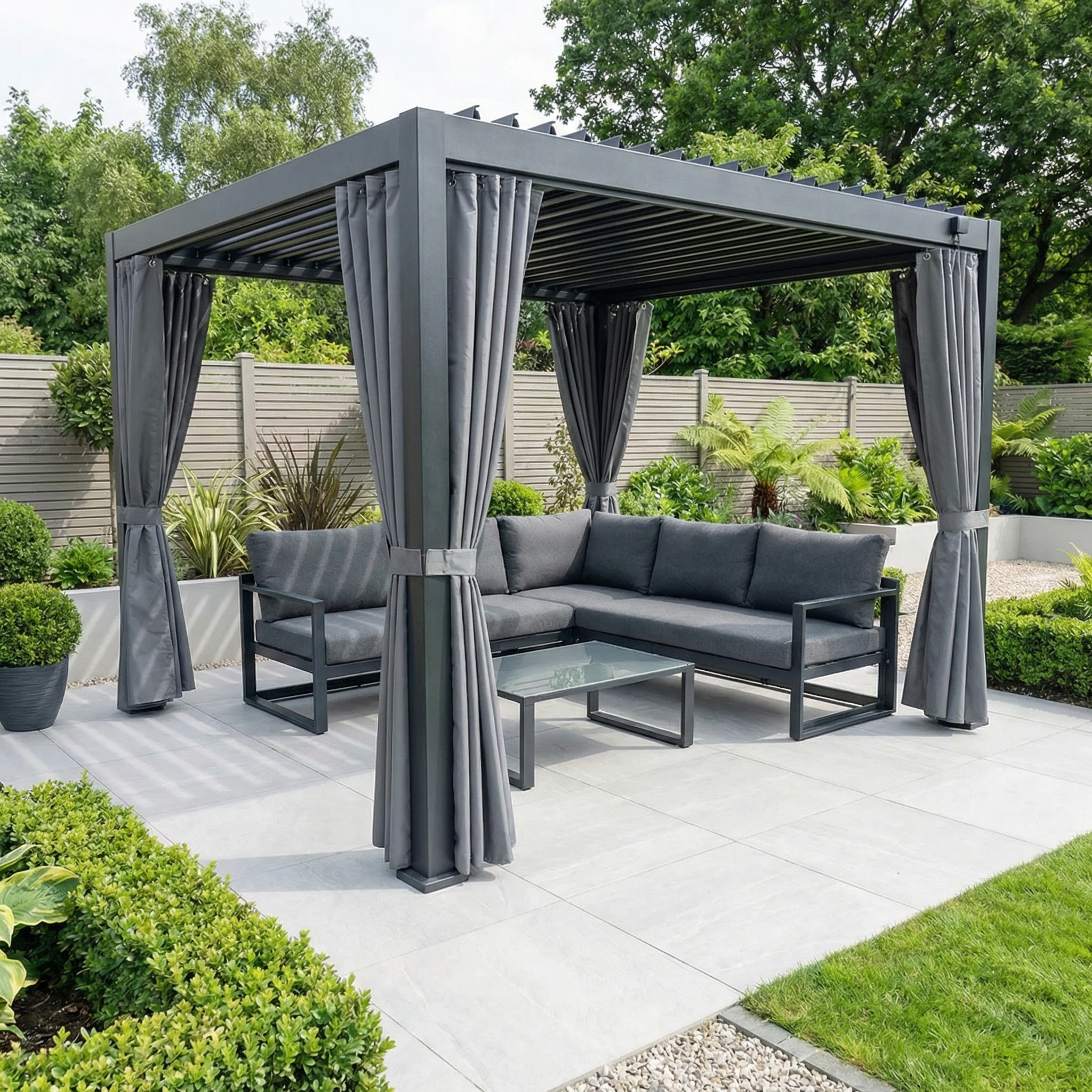Modern outdoor gazebo with PergoSTET Side Curtains for Lite 2.4m x 3m Pergola in Grey and patio furniture, set amid a landscaped garden with lush green plants.