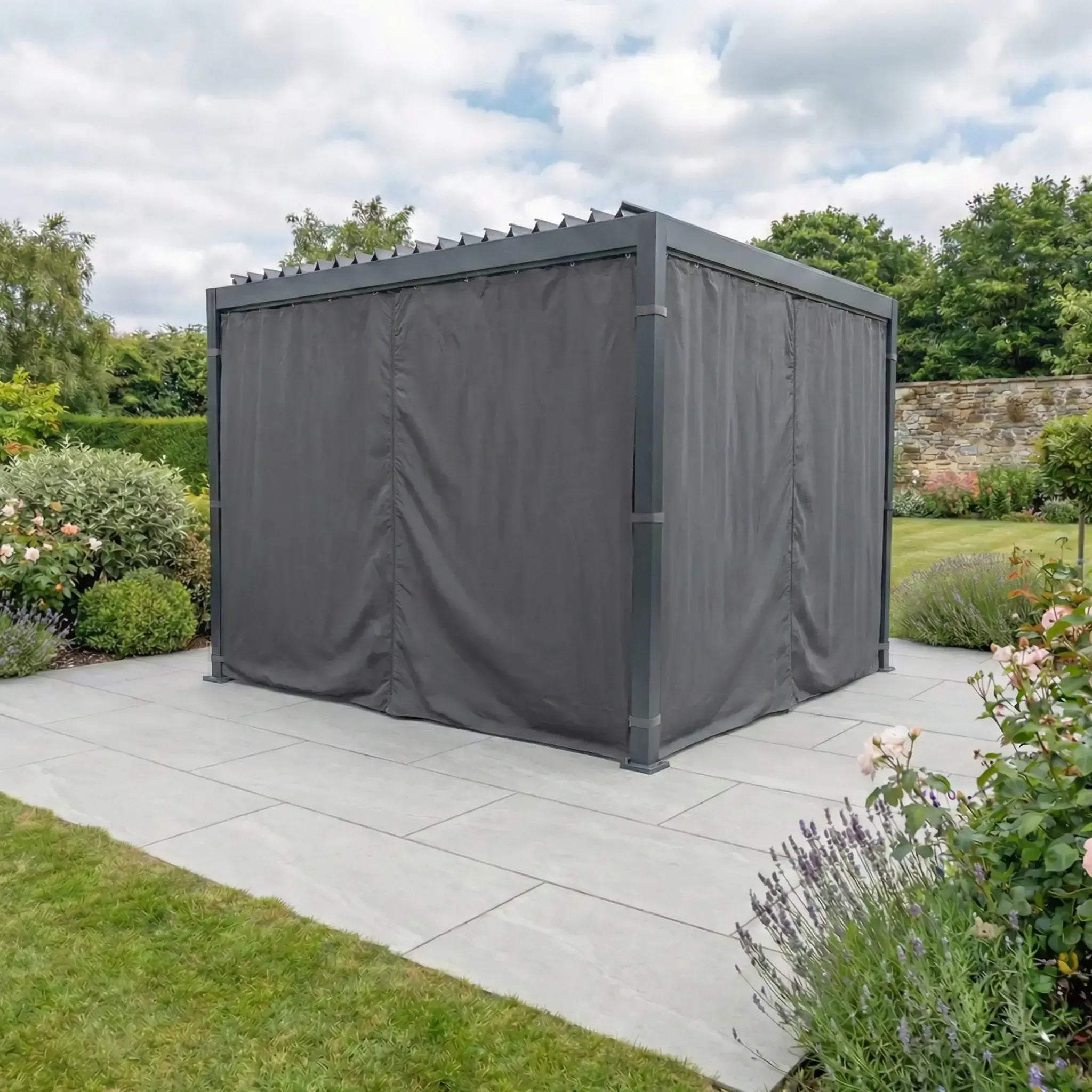 PergoSTET Side Curtains for Lite and Lite Neo 3m x 3m Square Pergola in Grey add weather protection to your outdoor pergola, shown on a tiled patio and surrounded by a lush green garden with flowers.