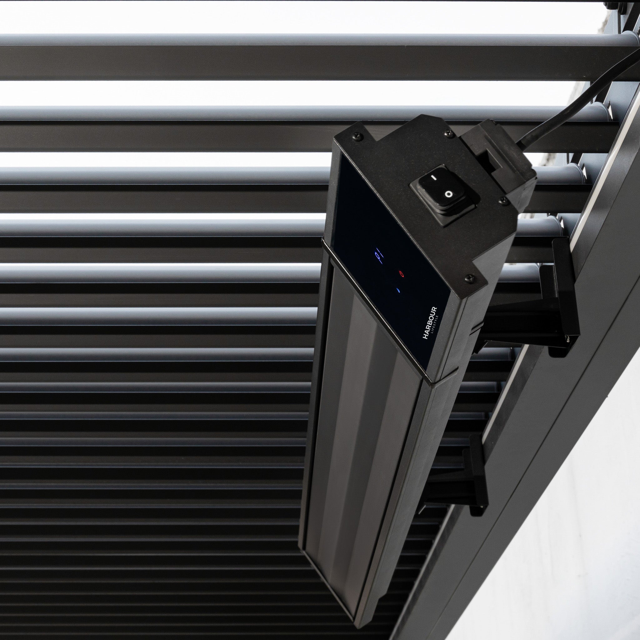 Close-up of the PergoSTET 2400W Wifi & Bluetooth Heater in Black, mounted on a metal slatted ceiling—ideal for outdoor heating beneath a pergola.