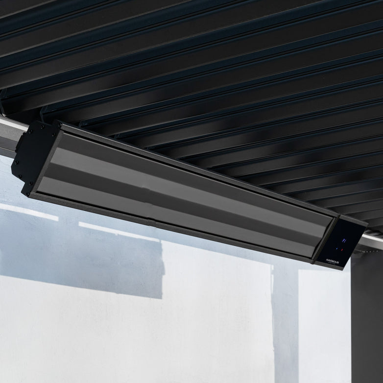 The PergoSTET 2400W Wifi & Bluetooth Heater in Black from Harbour Lifestyle is ceiling-mounted under a dark metal roof above a white wall—delivering stylish, smart outdoor heating ideal for pergola setups.