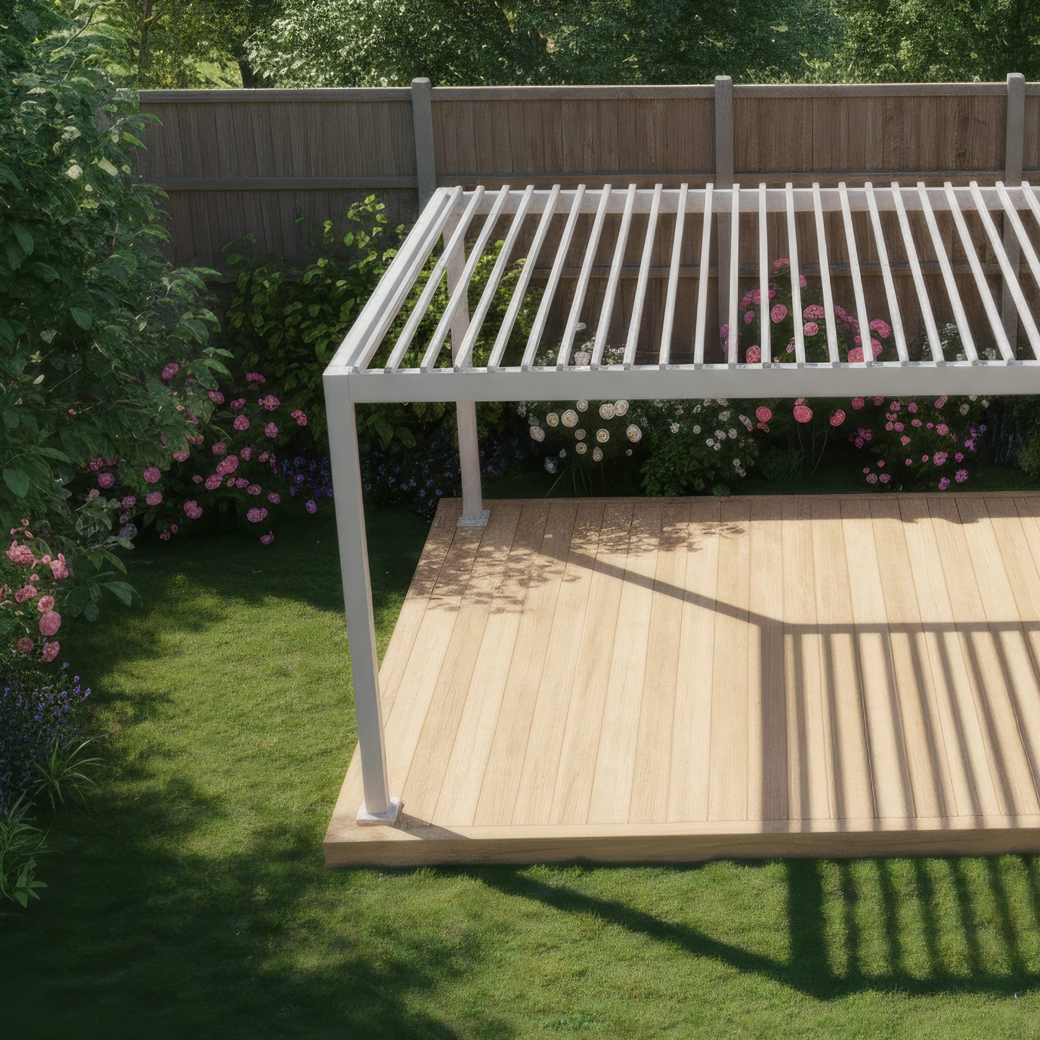 The PergoSTET Lite 3m x 3m Metal Square Pergola in Latte stands on a wooden deck in a flower-filled garden with a wooden fence, providing sleek shade and contemporary style.