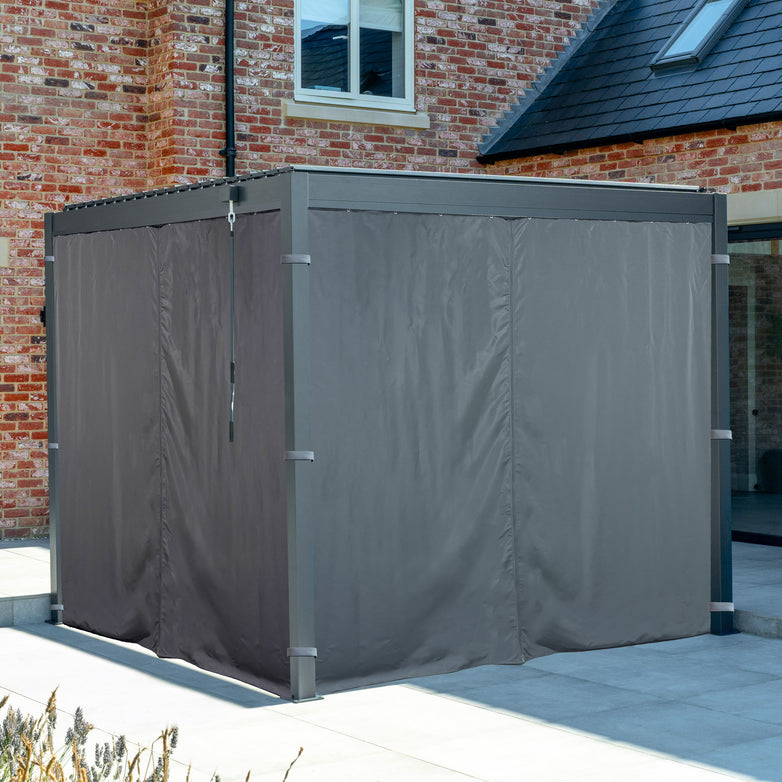 Grey PergoSTET Side Curtains for a Lite 3m x 3m Square Pergola add weather resistance to the outdoor gazebo on the patio by a brick house.