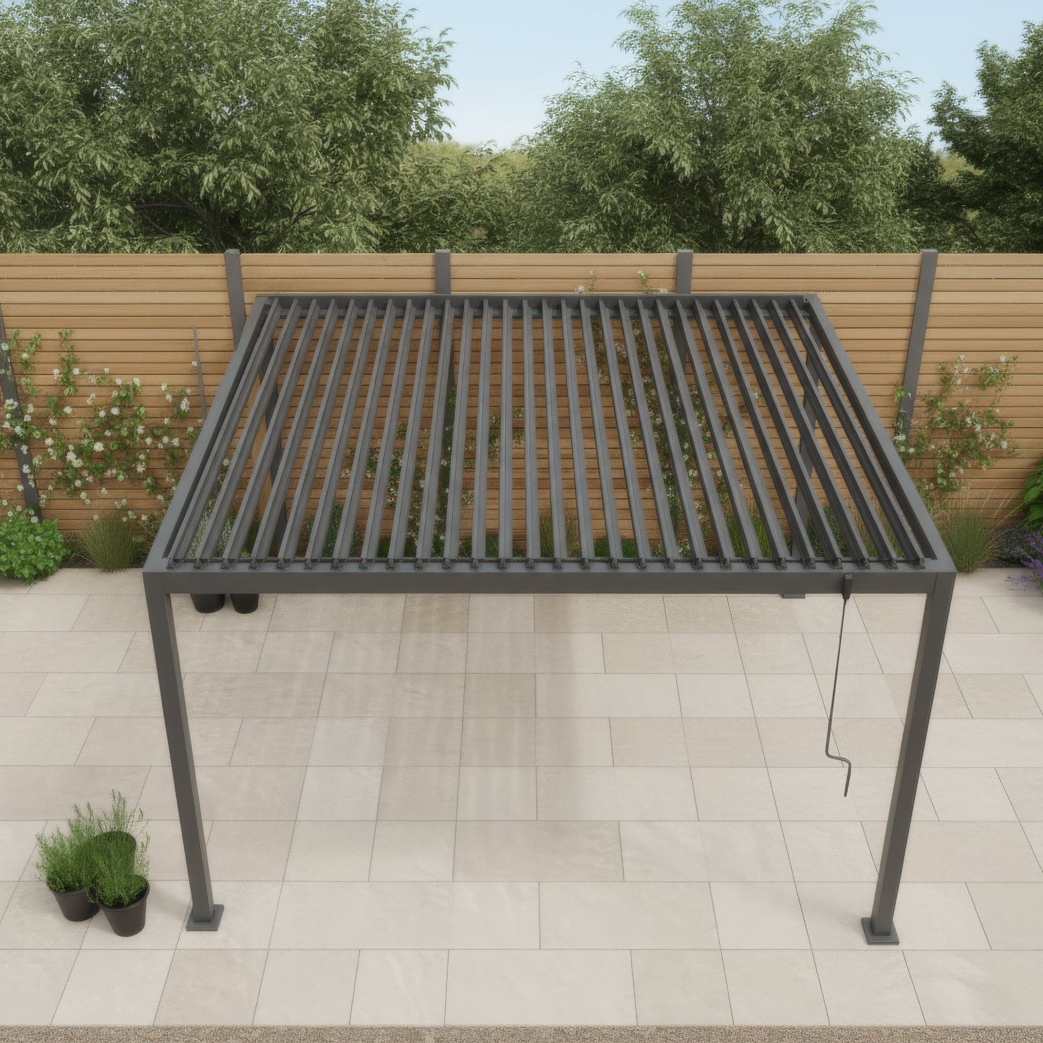 The PergoSTET Lite 3m x 4m Metal Rectangular Pergola in Grey stands on a tiled patio, featuring tilting louvres, and is surrounded by plants and a wooden fence.