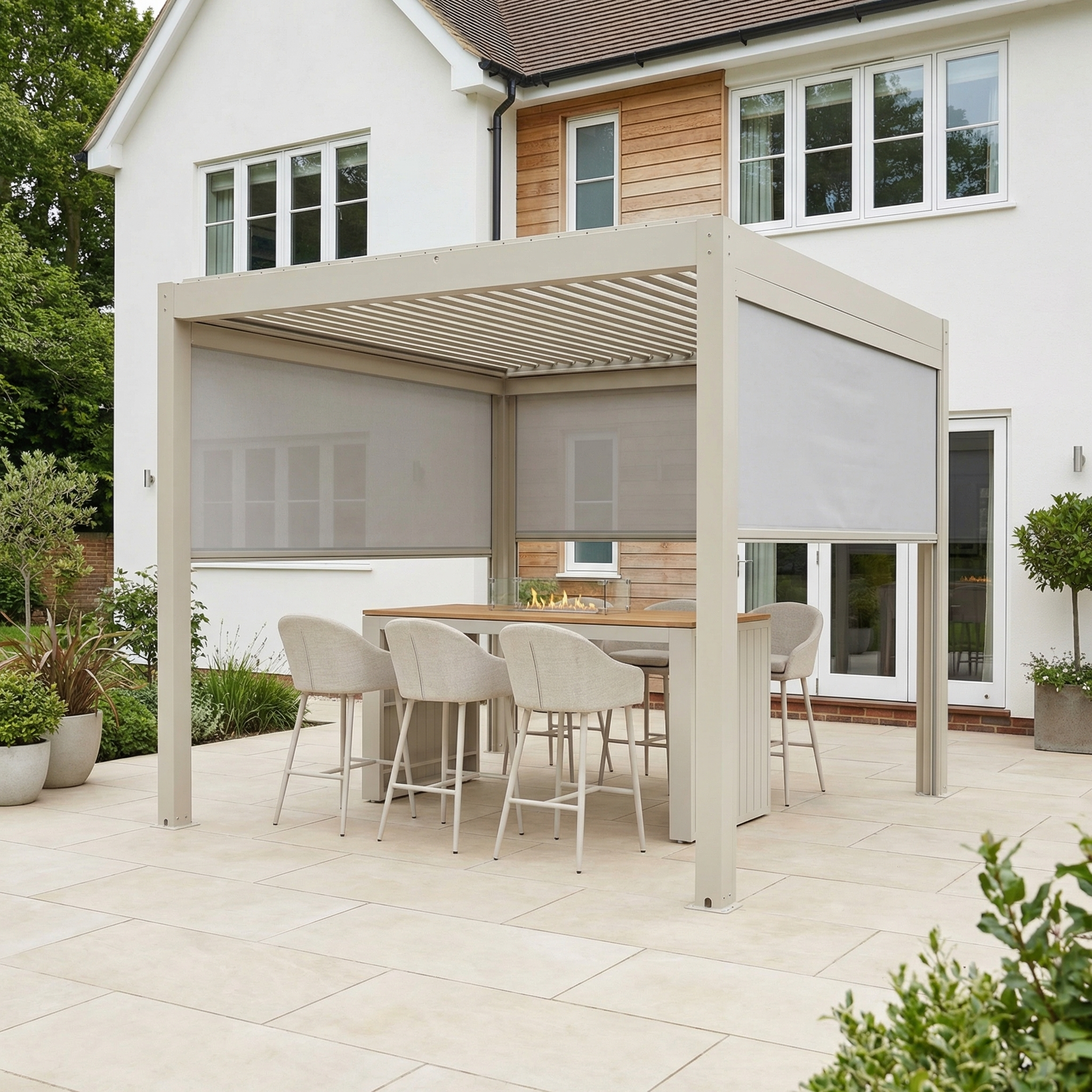 The PergoSTET Plus 3m x 3m Square Pergola with 3 Manual Side Blinds and LED Lighting in Latte covers an outdoor dining set on a tiled patio beside a white house.