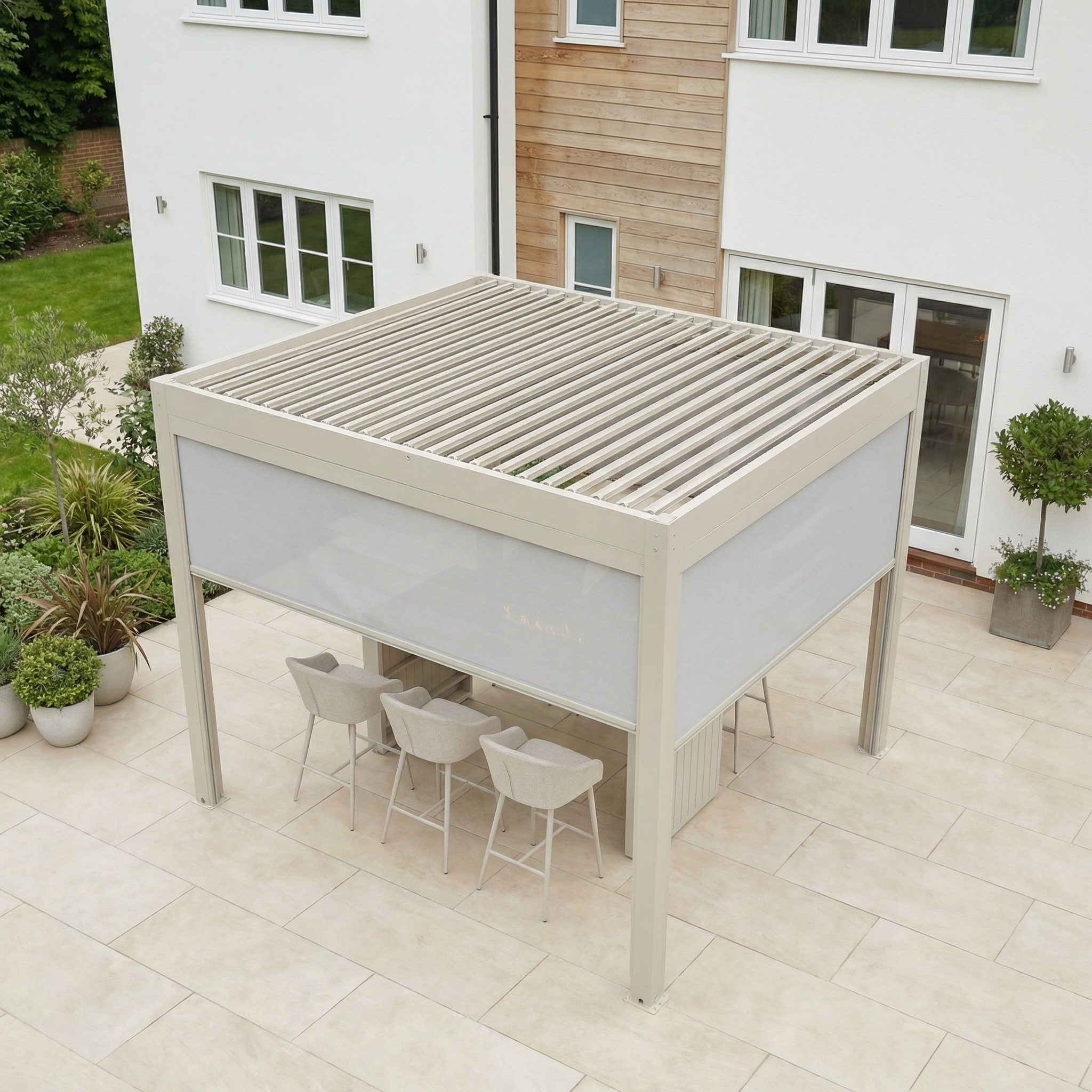 The PergoSTET Plus 3m x 3m Square Pergola in Latte features a louvred roof, LED lighting, and three manual Textilene side blinds, perfect for covering a patio dining area beside a contemporary house.