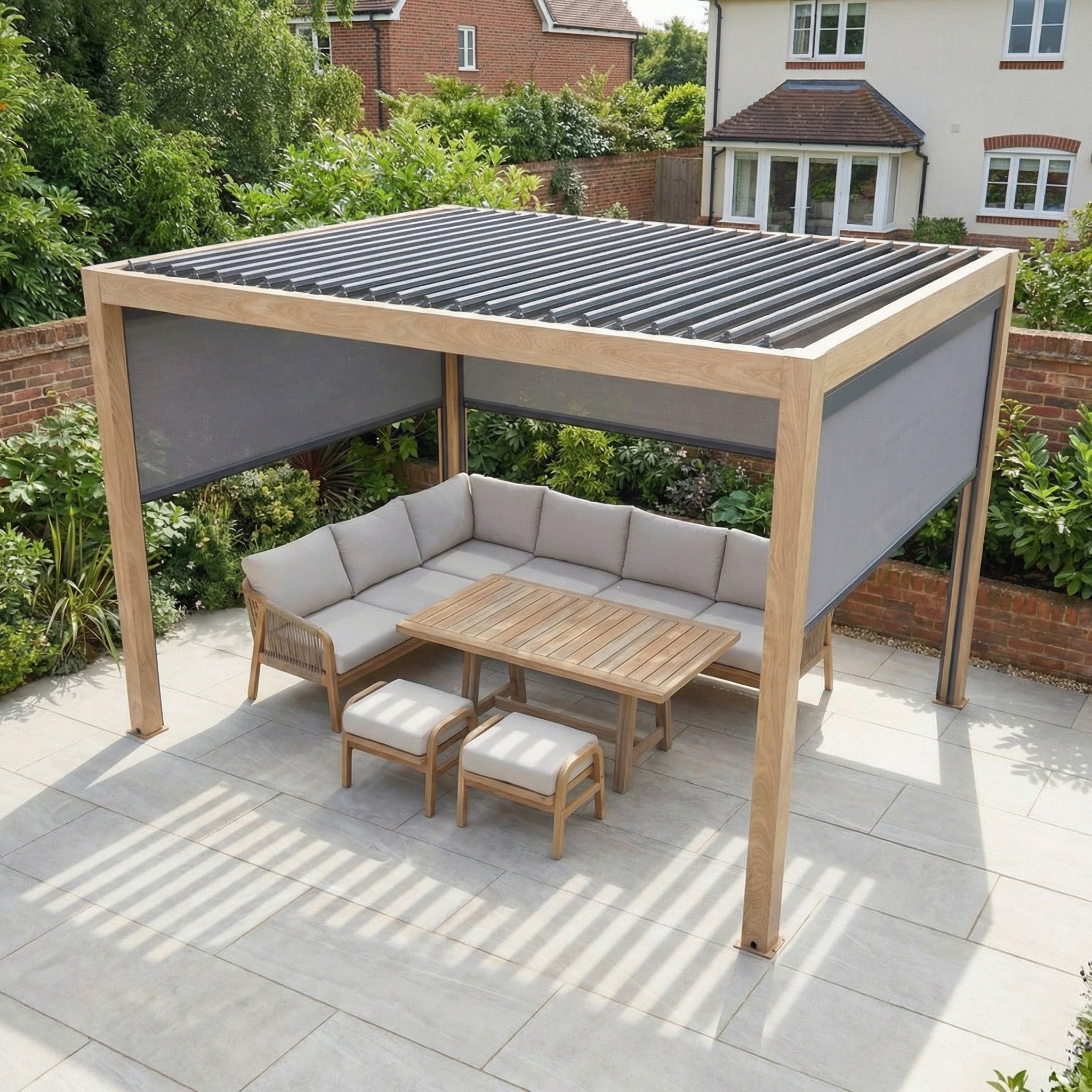 The PergoSTET Plus 3m x 4m Rectangular Pergola with 3 Manual Side Blinds and LED Lighting in Wood Effect features a stylish patio setup with a corner sofa, table, and two stools in a serene garden setting.