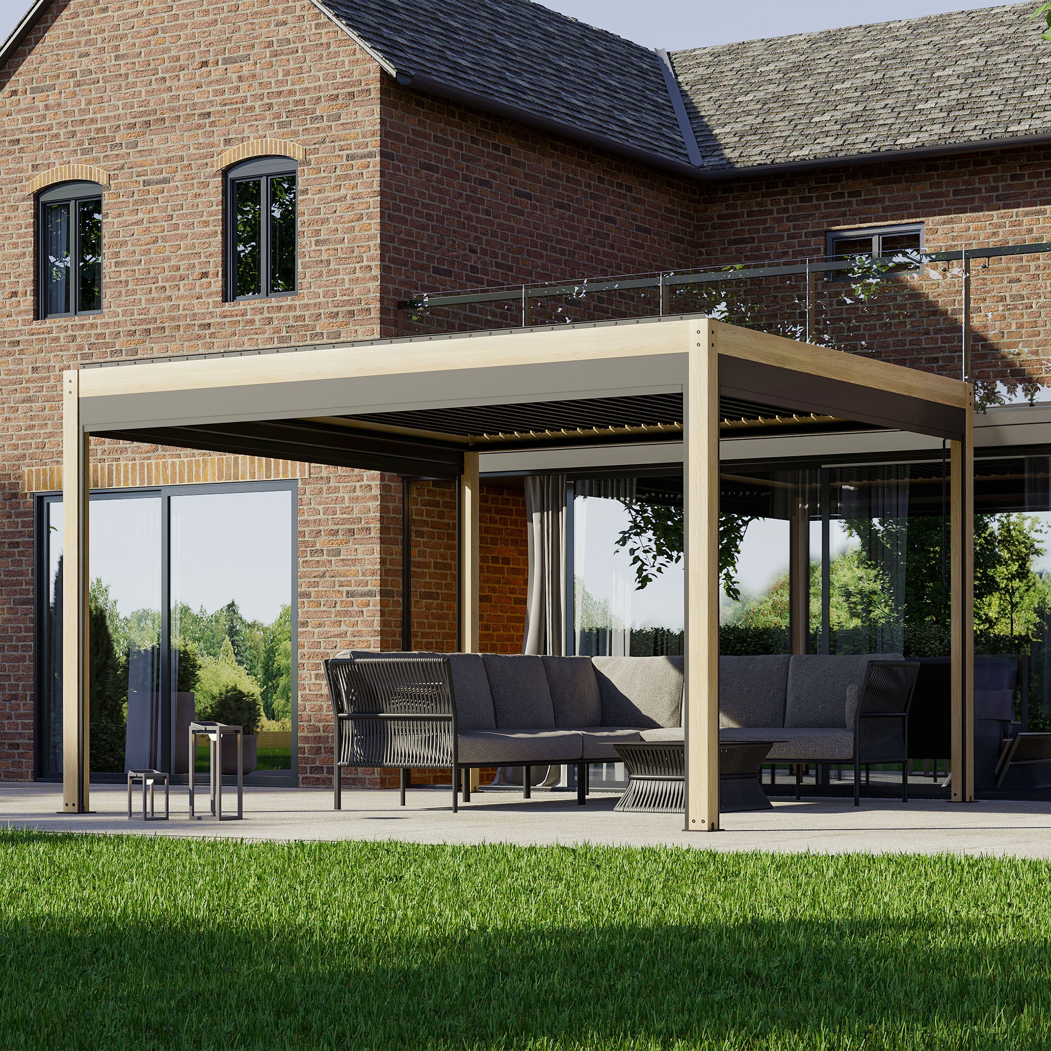 A modern patio with outdoor furniture under a PergoSTET Plus 3m x 4m Rectangular Pergola with 3 Drop Sides and LED Lighting with Wood Effect, next to a brick house, overlooks a green lawn.
