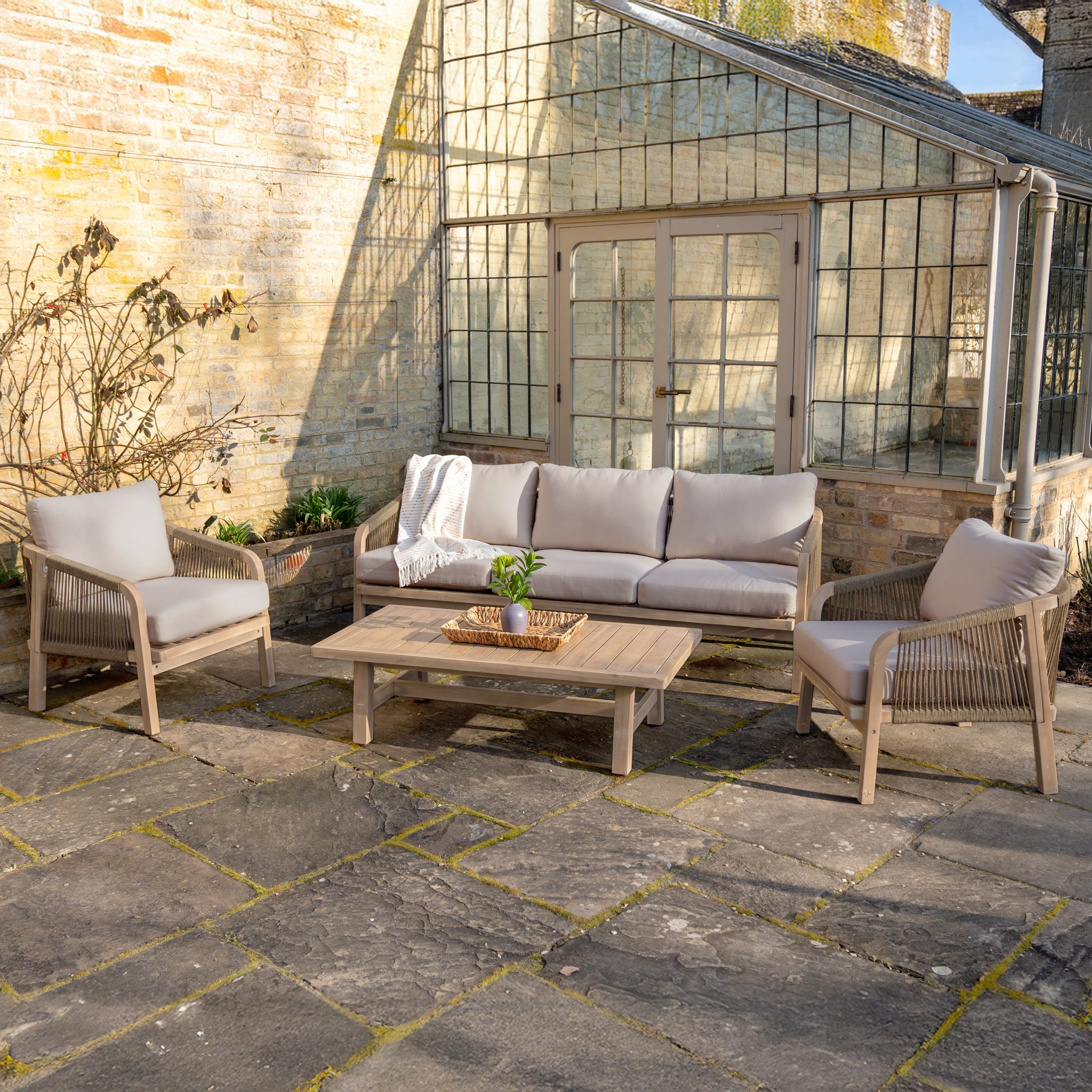 The Quay 3 Seat Sofa Set in Mocha features cushioned chairs, a sofa, and table—ideal for stylish outdoor relaxation beside your garden or greenhouse.