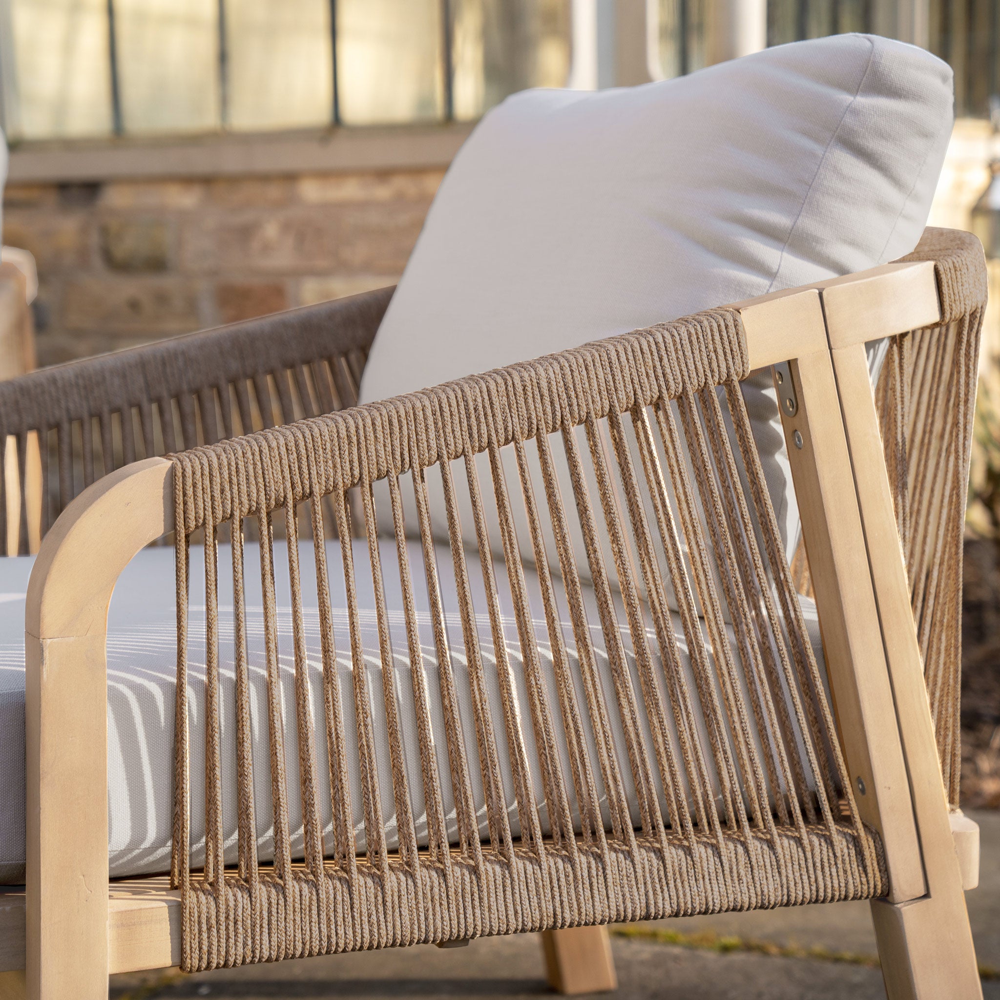 Close-up of the Quay 3 Seat Sofa Set in Mocha, showcasing a modern outdoor chair with rope-woven armrest and plush white cushions as part of this stylish garden ensemble.