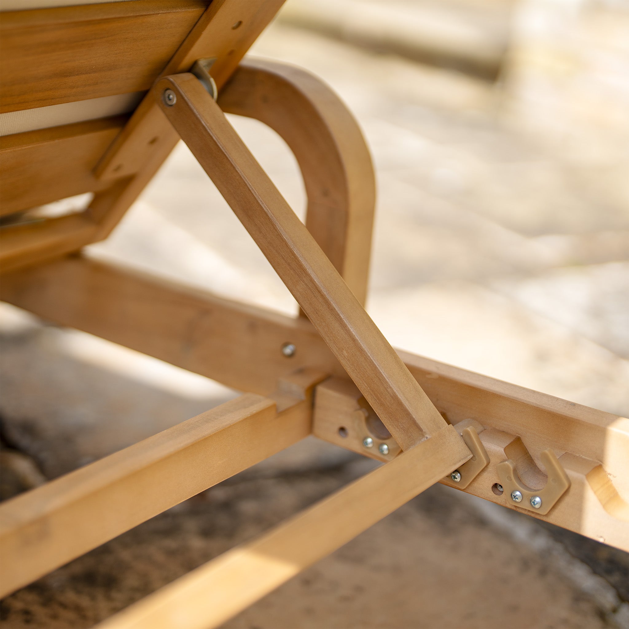 Close-up of a Quay Sun Lounger in Linen made from acacia wood, showcasing its adjustable support mechanism on a sunlit stone surface.