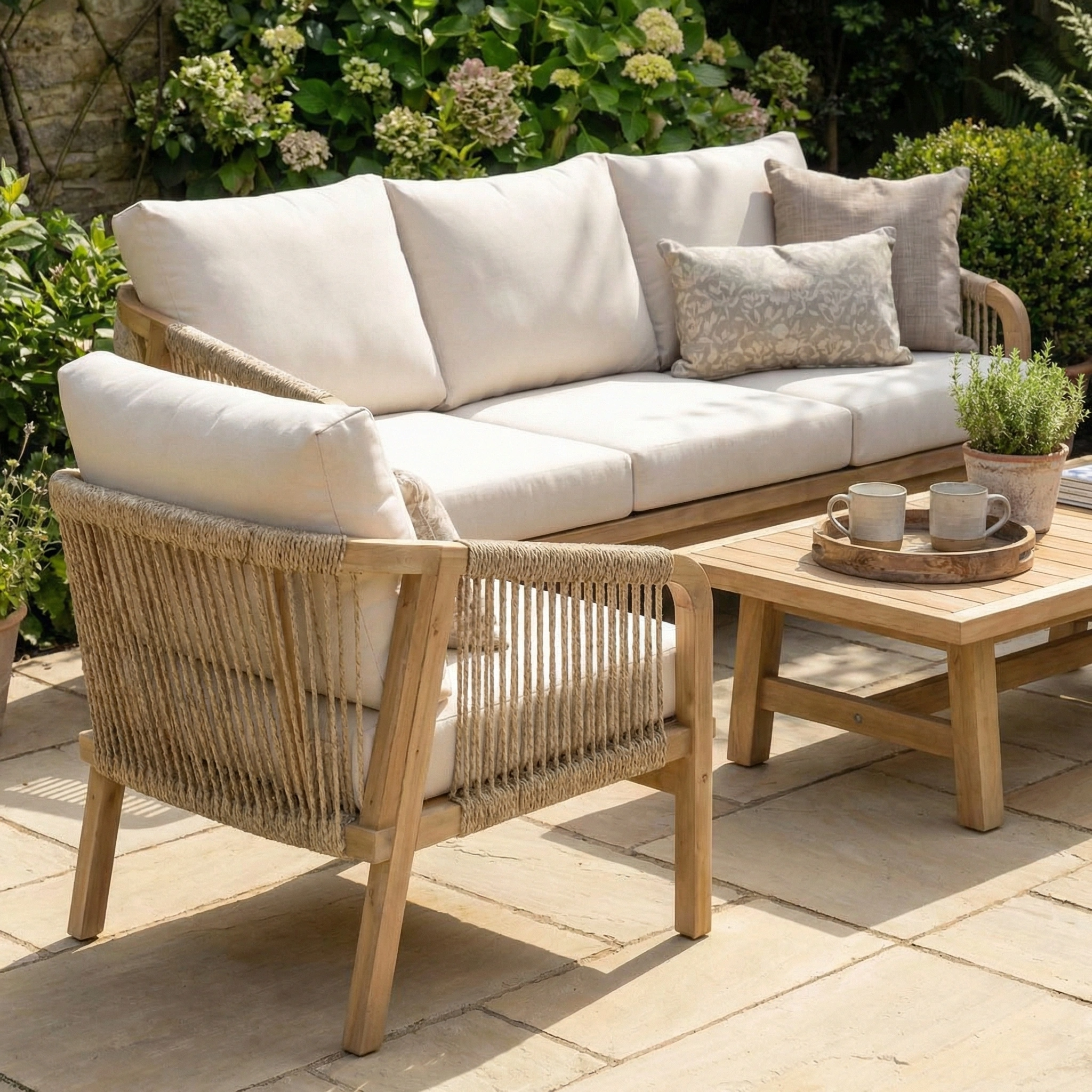 The Quay 3 Seat Sofa Set in Linen features stylish acacia wood frames, cream cushions, comfortable outdoor lounge chairs, and a matching coffee table—perfect for elegant garden patios.