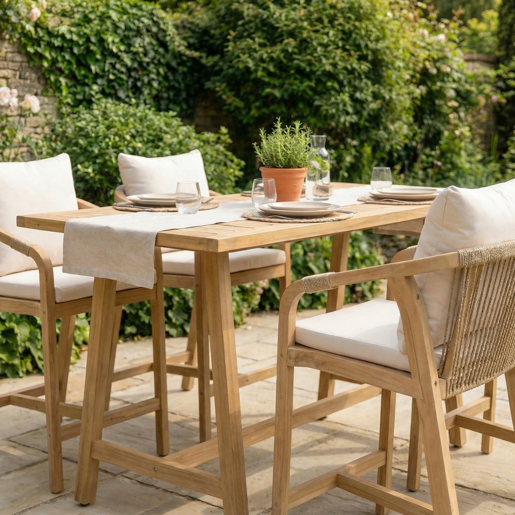 The Quay 4 Seat Rectangular Bar Set in Linen features cushioned chairs and a sturdy table, making it a perfect fit for your garden—an inviting addition to outdoor spaces surrounded by lush greenery.