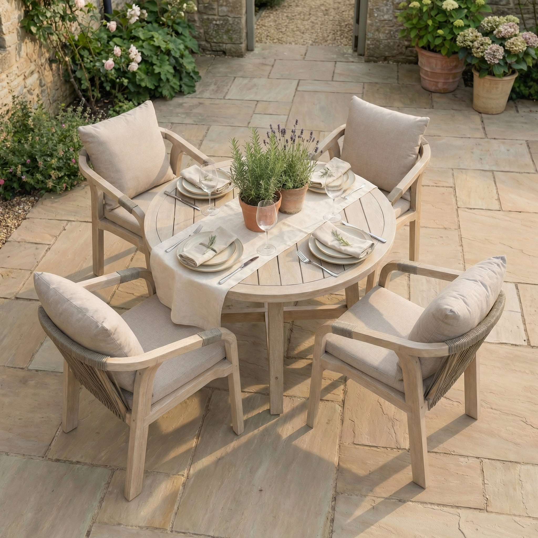Enhance your patio with the Quay 4 Seat Round Dining Set in Mocha, featuring a eucalyptus wood table, four cushioned chairs, place settings, and a potted lavender centerpiece—ideal for relaxing or entertaining outdoors.