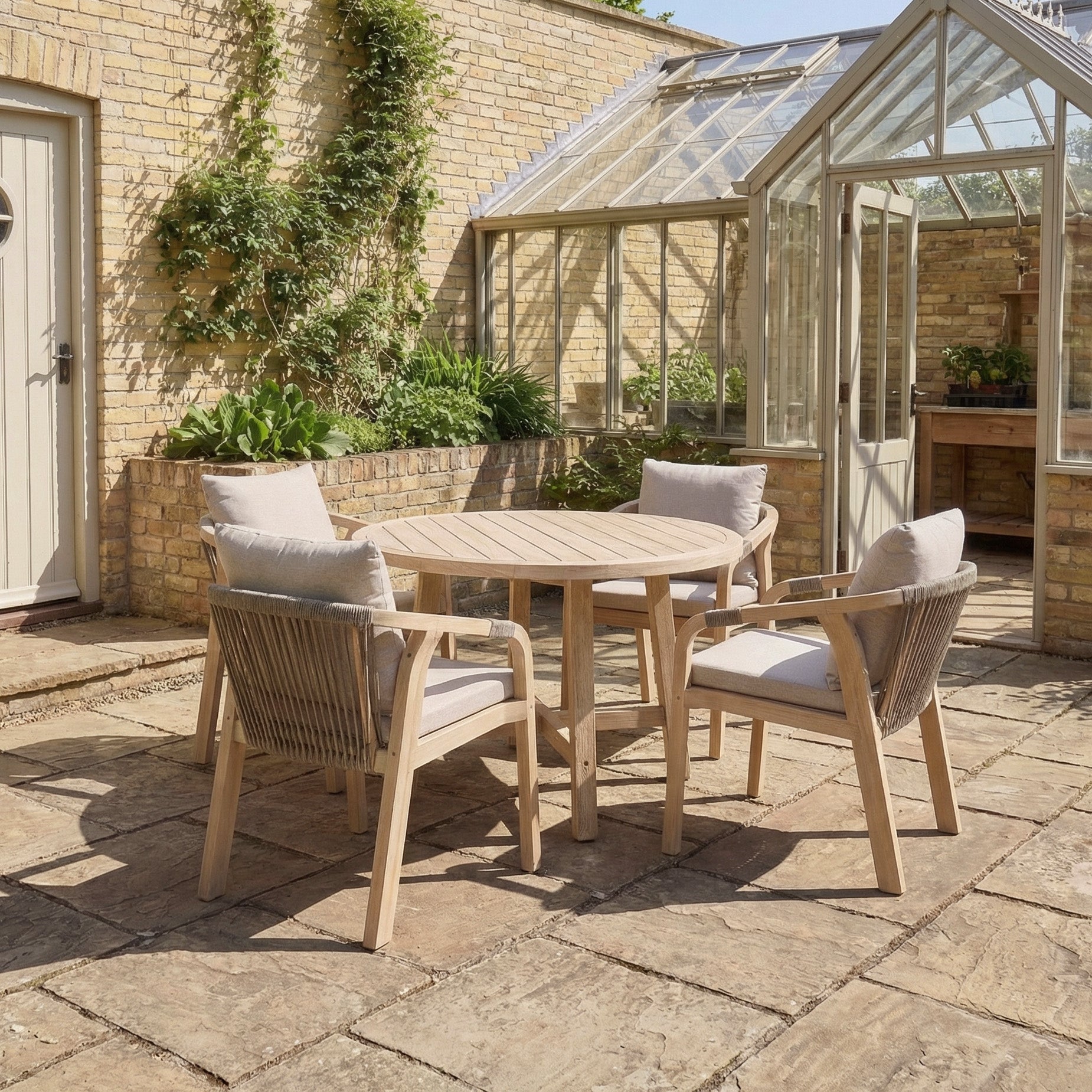 The Quay 4 Seat Round Dining Set in Mocha, crafted from durable eucalyptus wood, features four chairs and is ideal for stylish outdoor dining on patios or by greenhouses and brick walls.