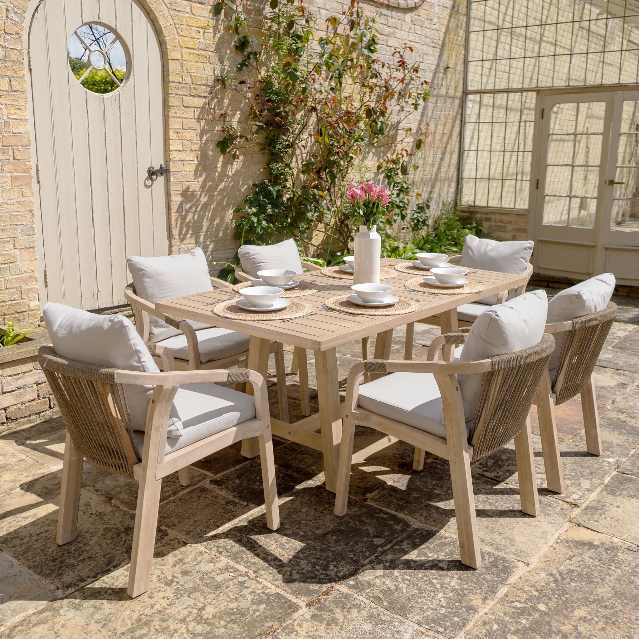 The Quay 6 Seat Rectangular Dining Set in Mocha features cushioned chairs and a sturdy wooden table, perfect for outdoor dining on your patio.
