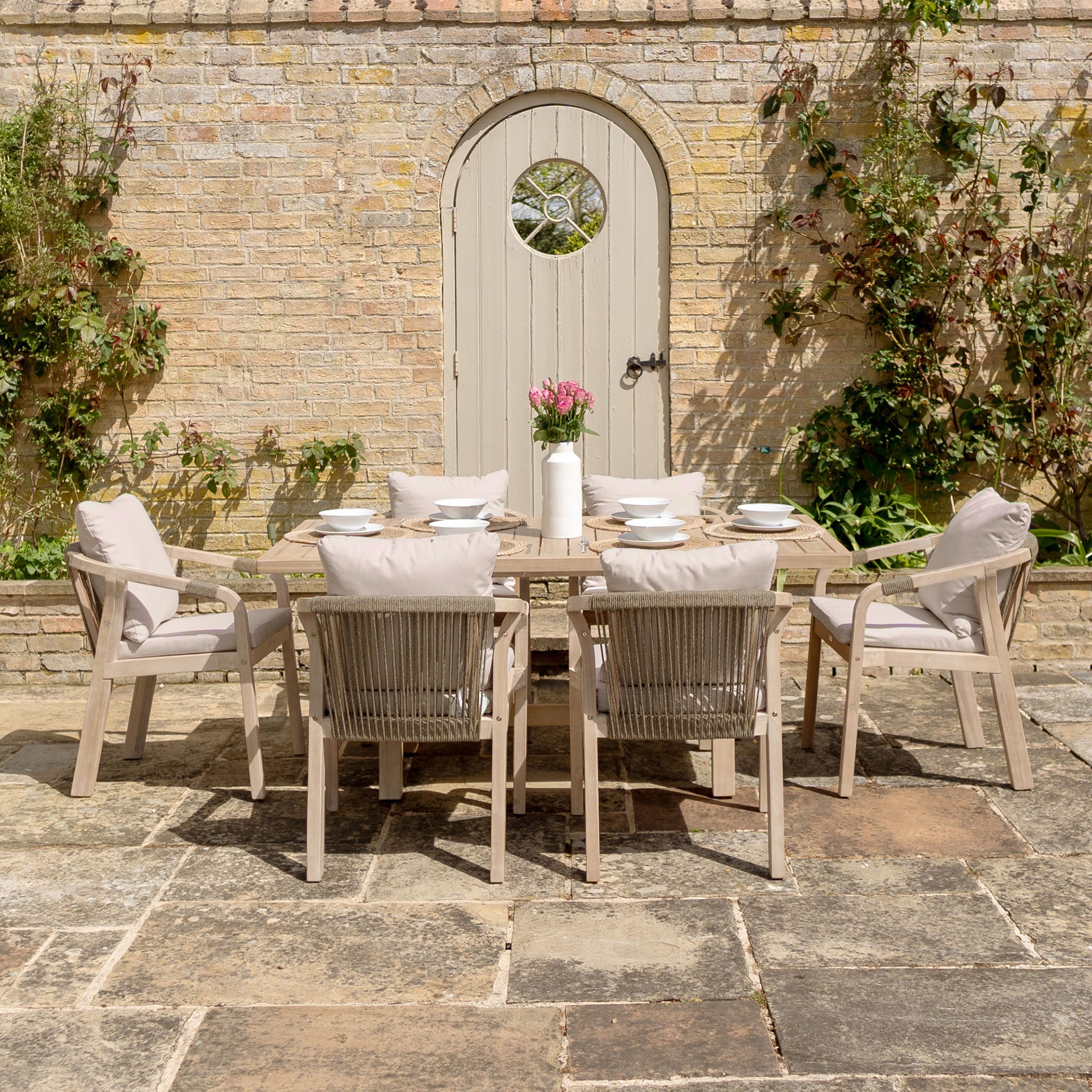 The Quay 6 Seat Rectangular Dining Set in Mocha features a sturdy eucalyptus frame and six cushioned chairs—ideal outdoor furniture for stylish gatherings on your patio or by the garden door.