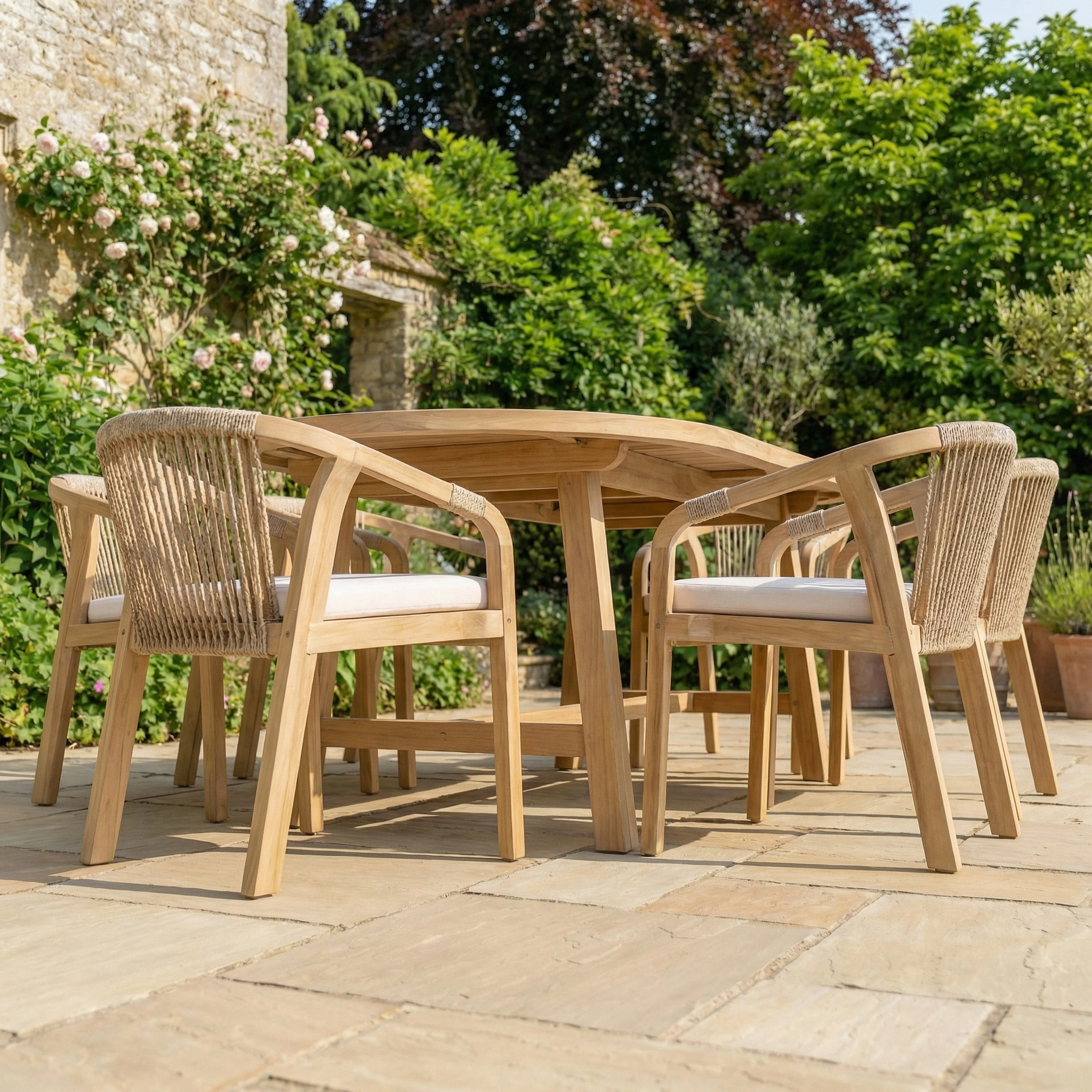 The Quay 8 Seat Oval Dining Set in Linen features rope-back chairs, ideal for stylish outdoor dining on a garden patio surrounded by climbing roses.