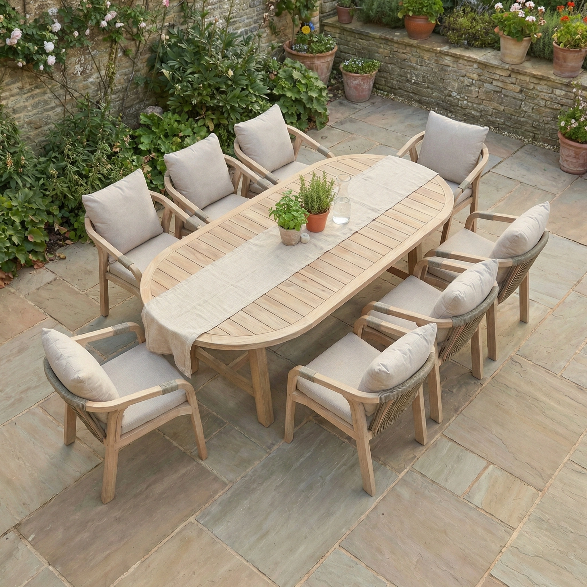 The Quay 8 Seat Oval Dining Set in Mocha features cushioned chairs on a stone patio, surrounded by potted plants—perfect eucalyptus wood garden furniture for stylish outdoor dining.