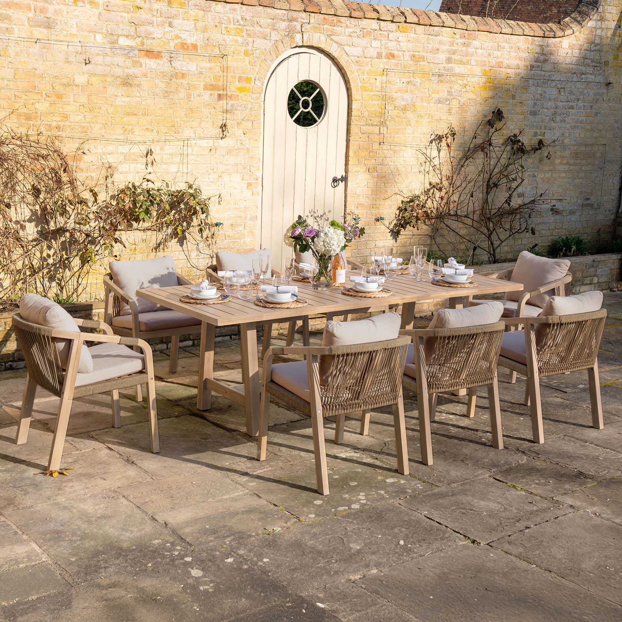 The Quay 8 Seat Rectangular Dining Set in Mocha includes eight cushioned chairs and a wooden table, making it ideal for outdoor dining on your stone patio.