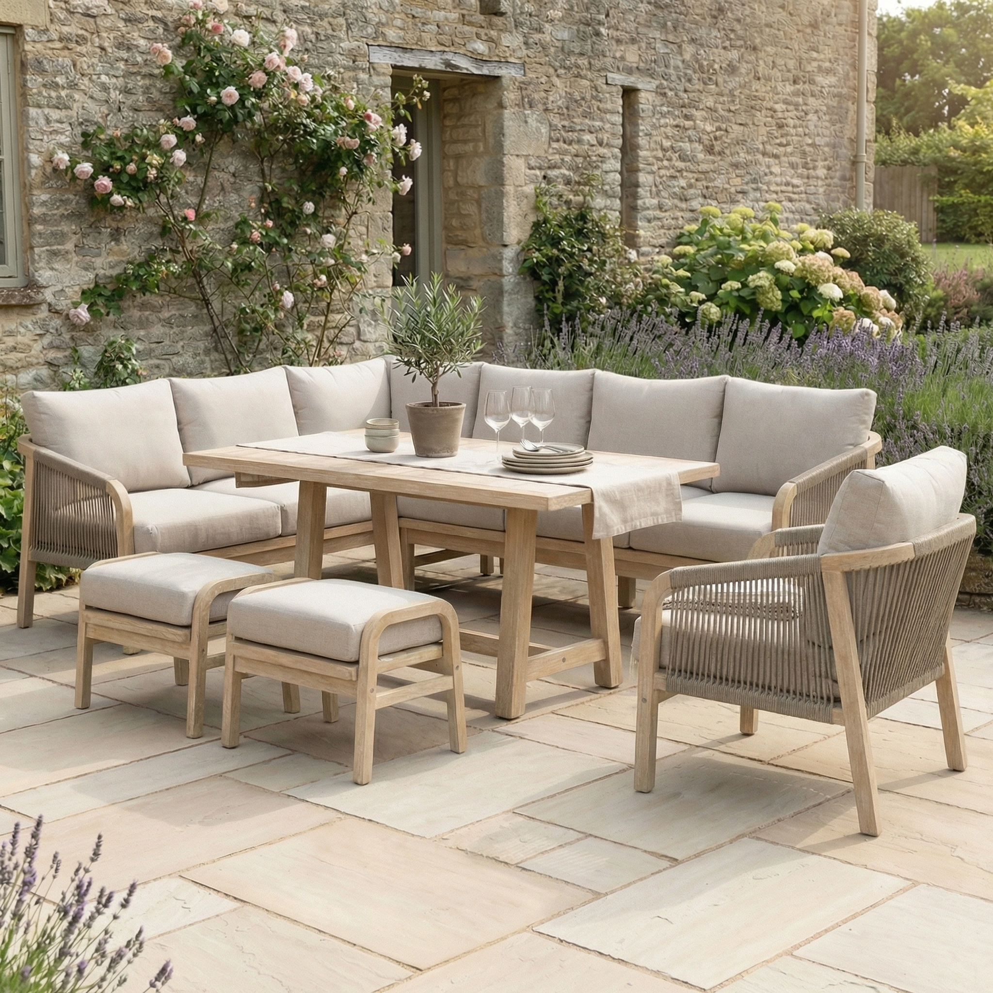 The Quay Corner Dining Set with Armchair in Mocha features water-resistant cushions and is perfect for a stone terrace, surrounded by blooming flowers and lush plants.