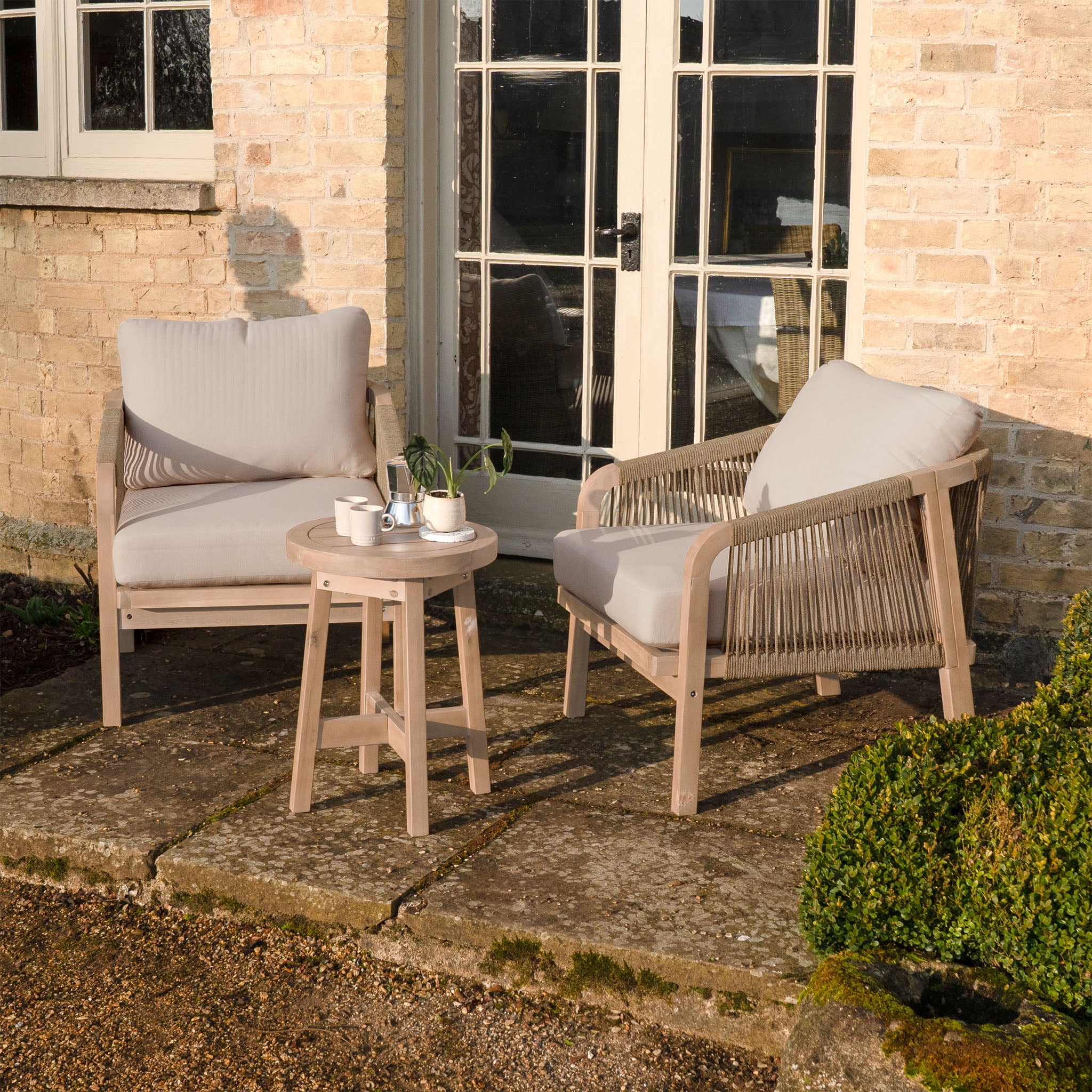 The Quay Lounge Set in Mocha features two cushioned chairs and a small round table, creating a stylish and comfortable outdoor seating area for your patio or garden.