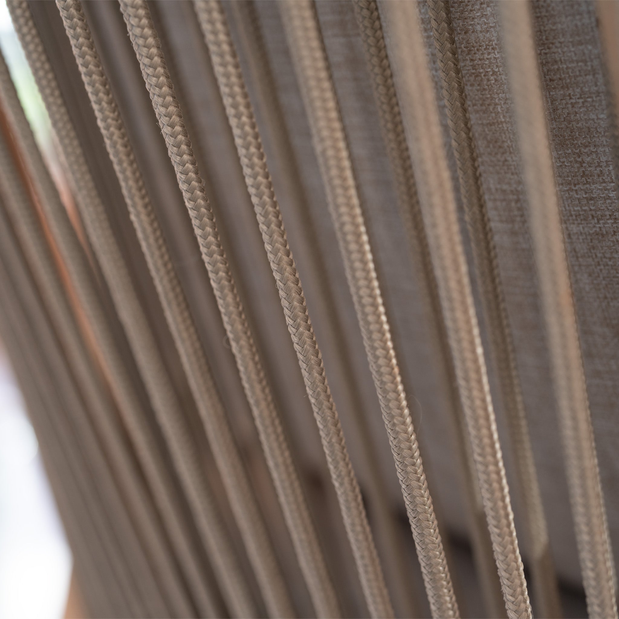 Close-up of parallel beige ropes against a fabric background, reflecting the woven textures found in the Quay 4 Seat Round Dining Set in Mocha.