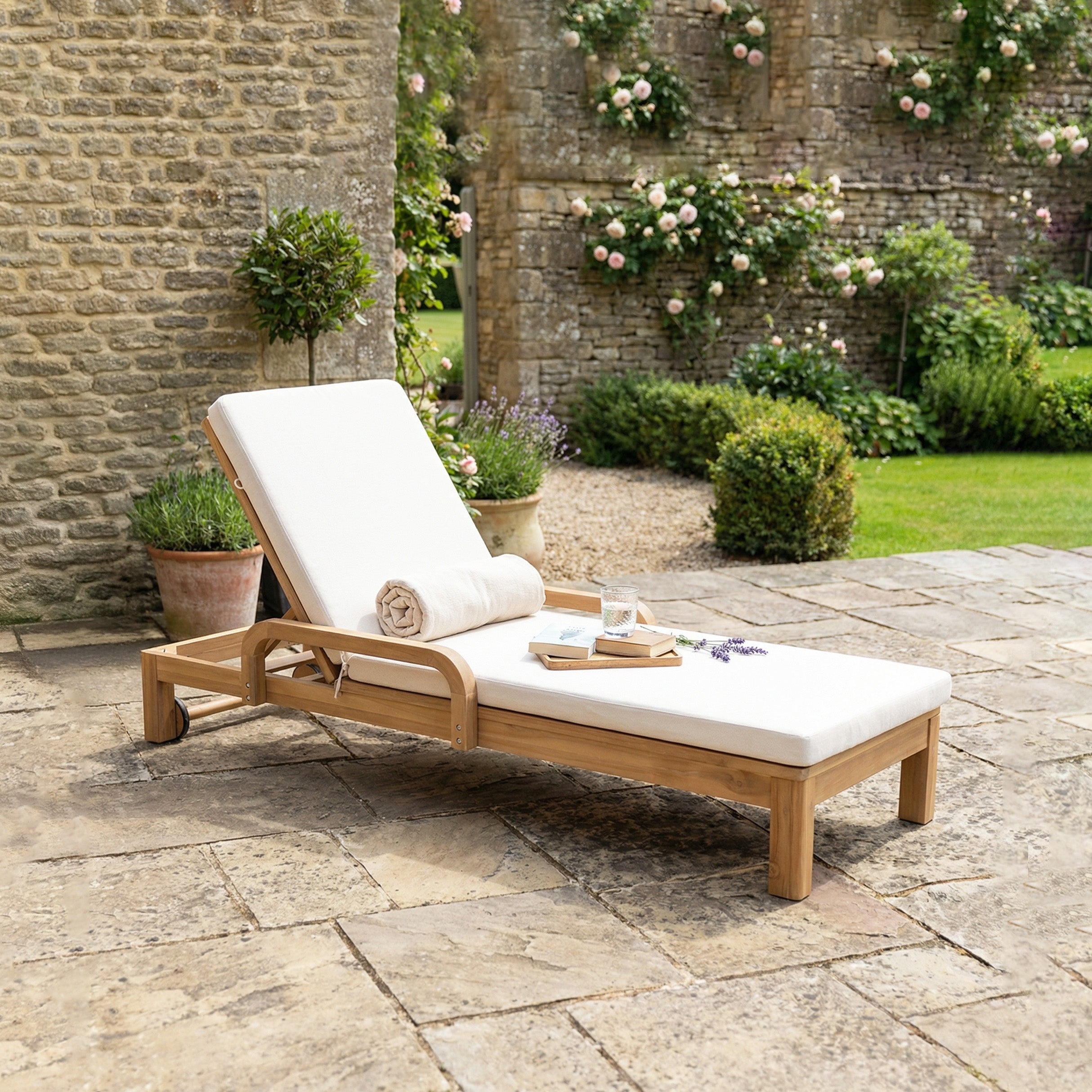 The Quay Sun Lounger in Linen—a cushioned acacia wood lounger with space for a towel, book, and drinks—is perfect outdoor furniture for relaxing on a garden patio.