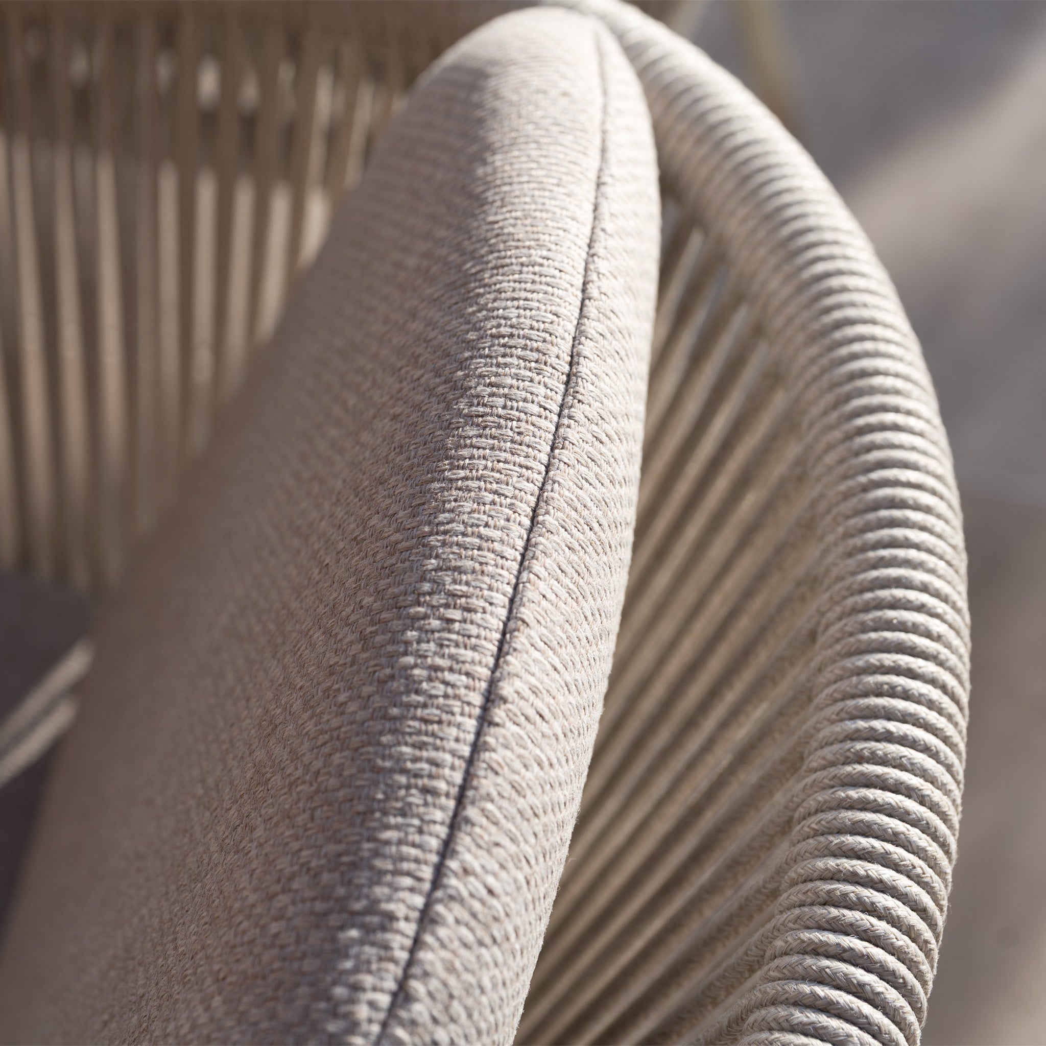 Close-up of a beige chair with curved armrest and woven rope detail from the Ravona 6 Seat Rope Extending Dining Set (162-222cm) in Latte, featuring a sturdy aluminium frame—ideal for outdoor dining.