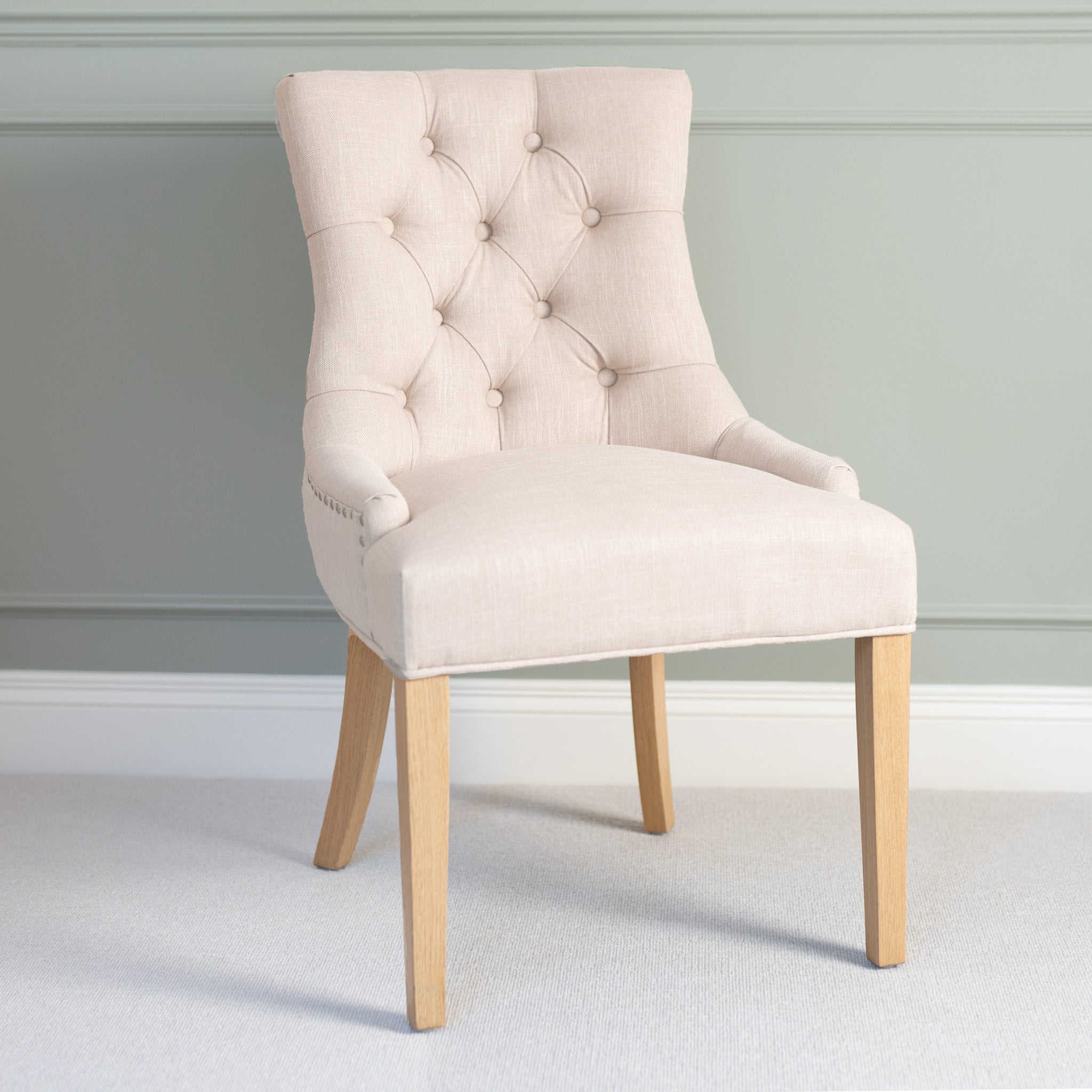 Regent Chair Set of 2 in Ivory featuring button tufting and wooden legs, styled against a light green wall for a modern look.