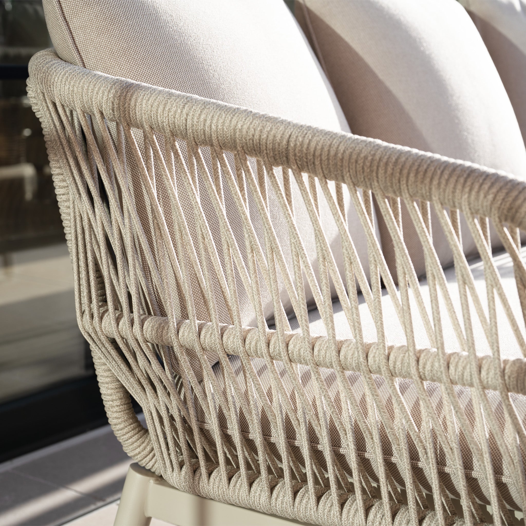 Close-up of the Rhea 2 Seat Sofa Set in Latte, showcasing beige aluminum frame, woven rope sides, and cushioned seats, all highlighted by natural sunlight.