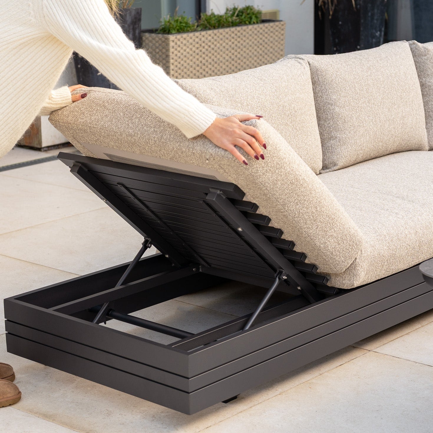 Lifting the backrest of the Savona Luxury Outdoor Large Corner Sofa Set with Altura Rising Table in Truffle reveals hidden storage, showcasing stylish and functional modular garden furniture.