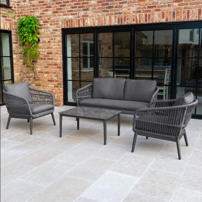 Transform your outdoor area with the Rhea 2 Seat Sofa Set in Grey, featuring two chairs, a 2 seat sofa, and a table arranged on a tiled patio near glass doors—ideal for creating an inviting outdoor living space. Expertly crafted from durable aluminium garden furniture, this stylish set delivers both comfort and contemporary elegance for any patio or garden.